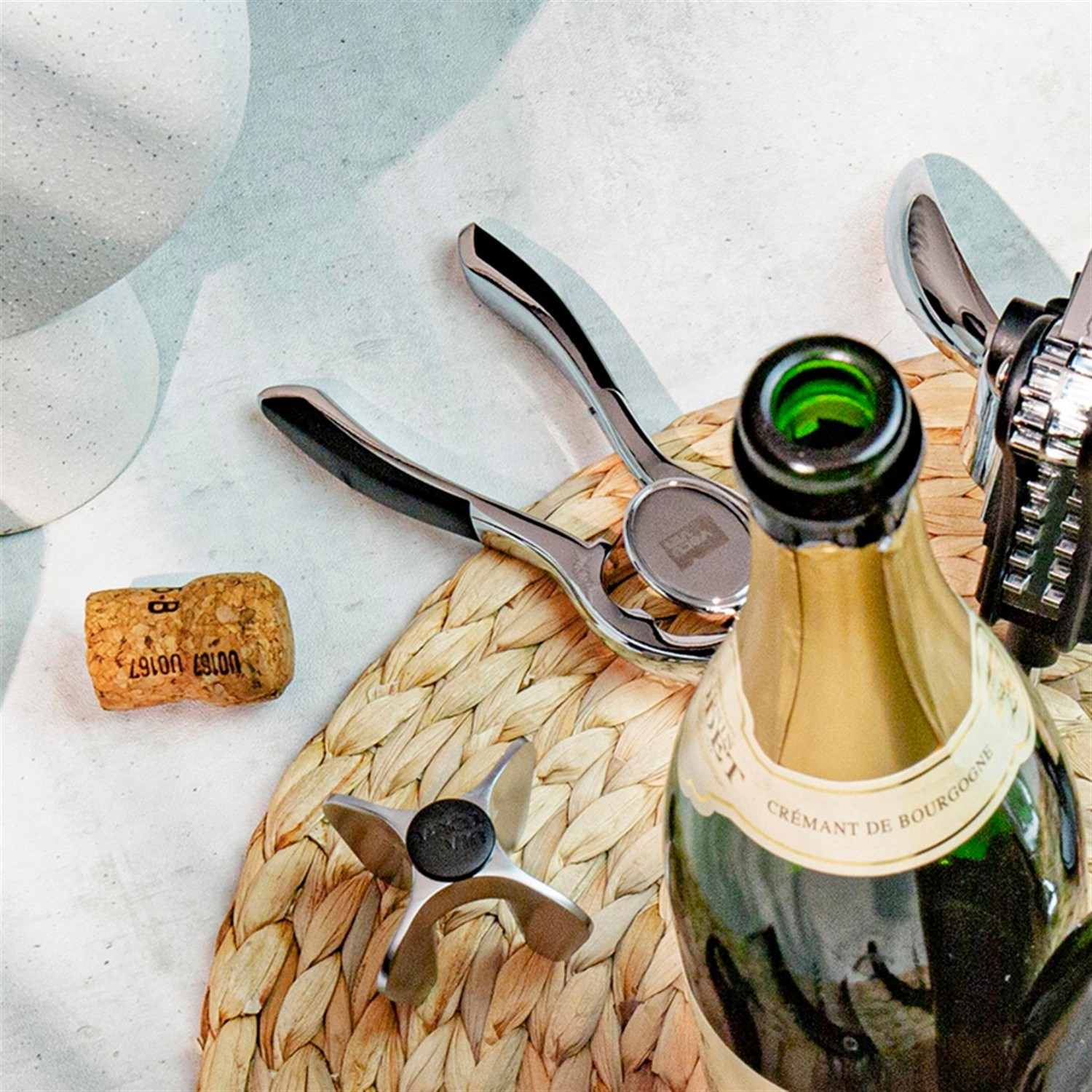 Şampanya mantarı, tirbuşon ve örgü servis altlığında Crémant de Bourgogne şişesi.