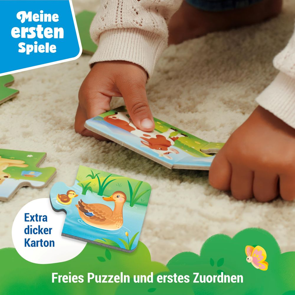 Bambino gioca con pezzi di puzzle: anatra sull'acqua, mucca sul prato, farfalla.