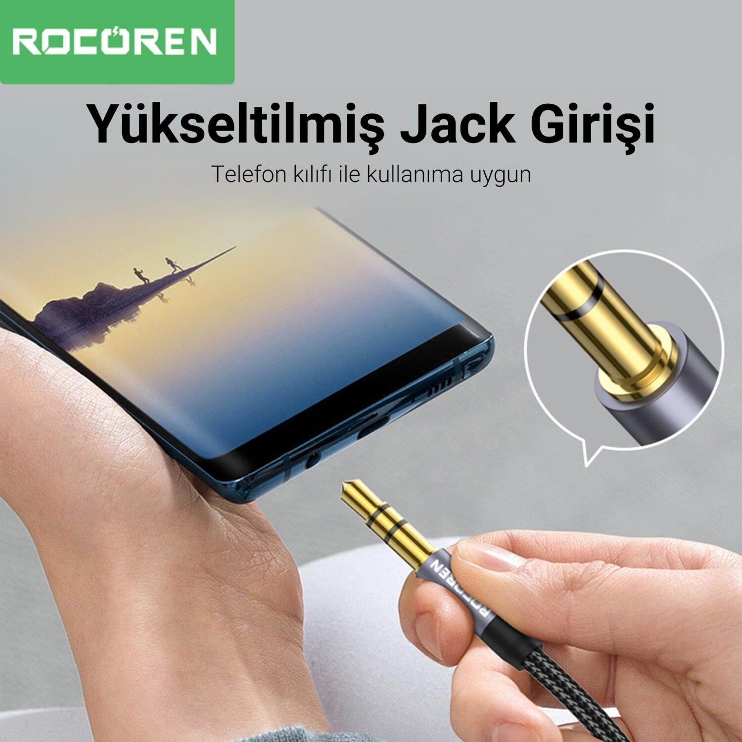 Bir el, telefon ve altın rengi 3,5 mm ses jak fişini tutuyor.
