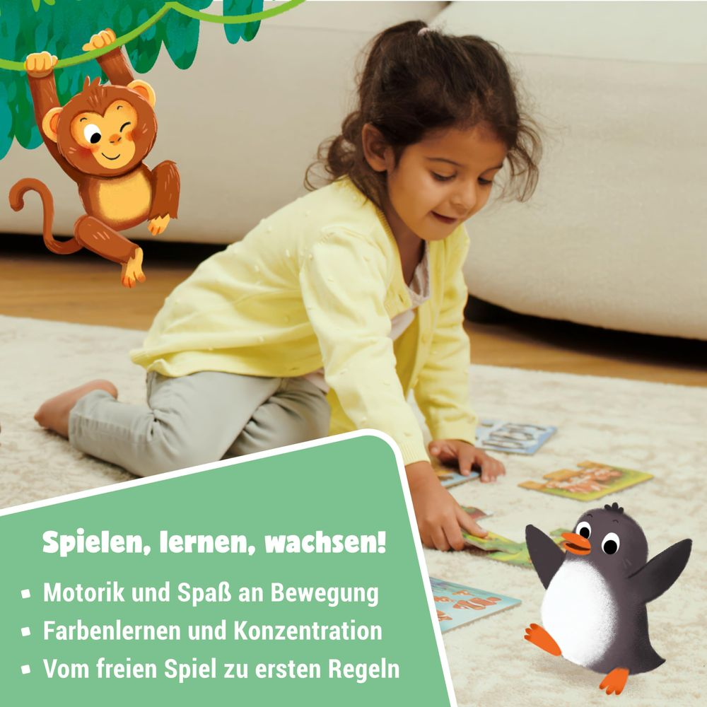 Una bambina gioca con le carte per terra, accanto a una scimmia e un pinguino.
