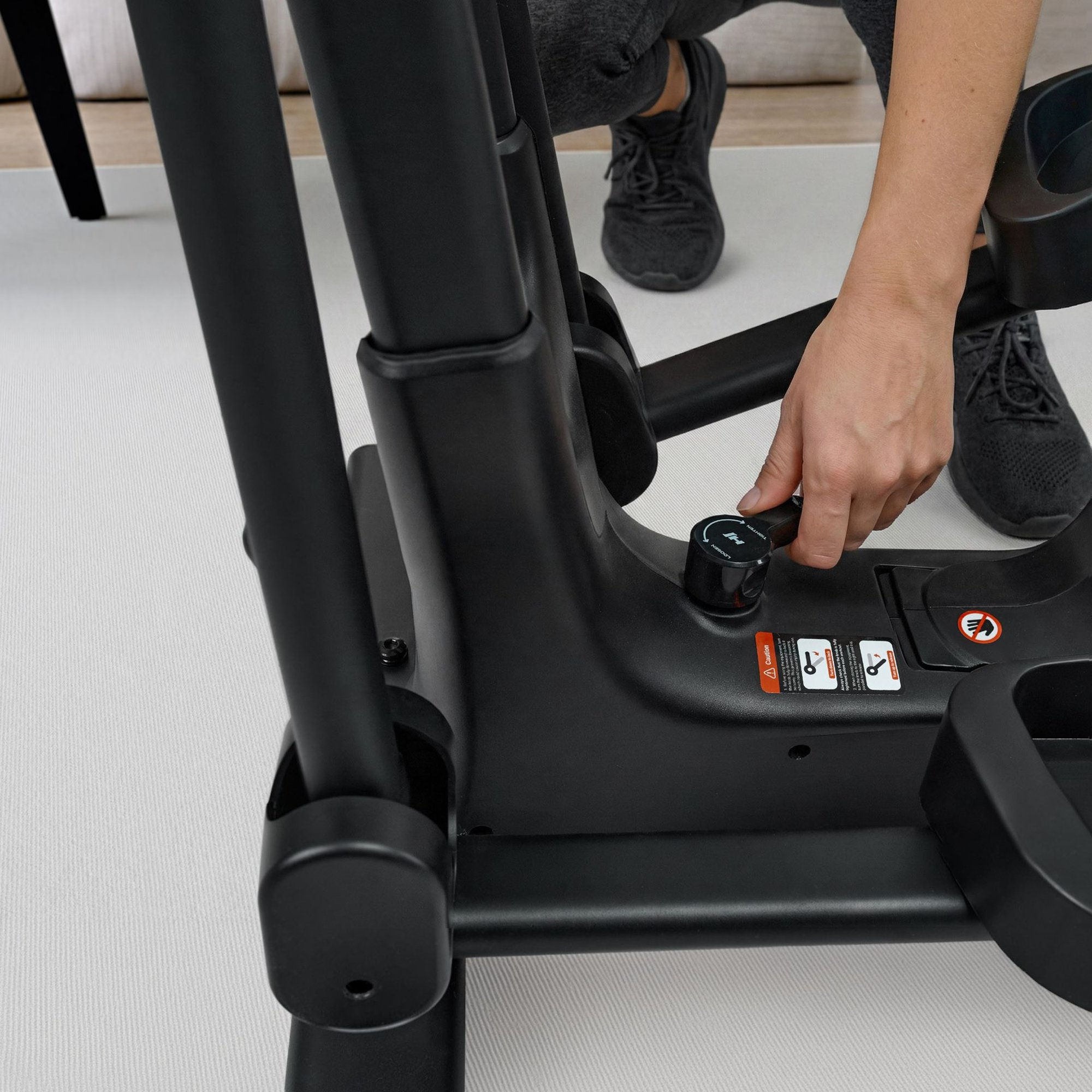 Eine Hand dreht einen Knopf an einem schwarzen Trainingsgerät.