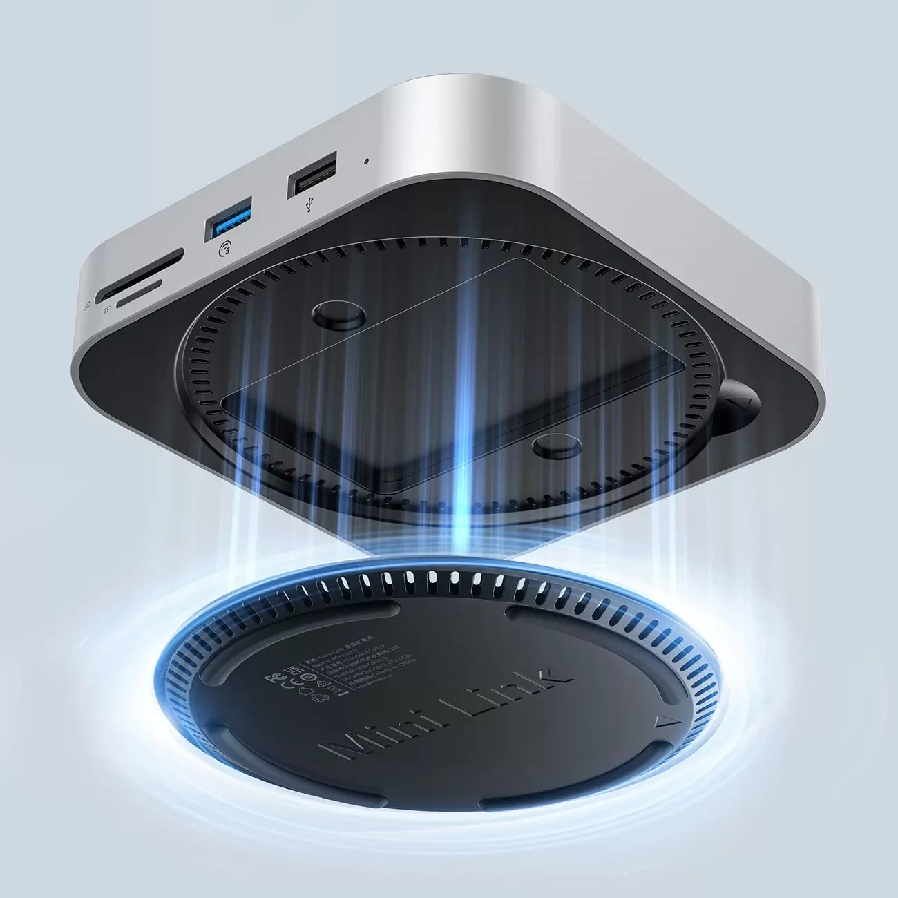 Srebrny mini PC z portami SD i USB, nad czarnym wentylatorem.