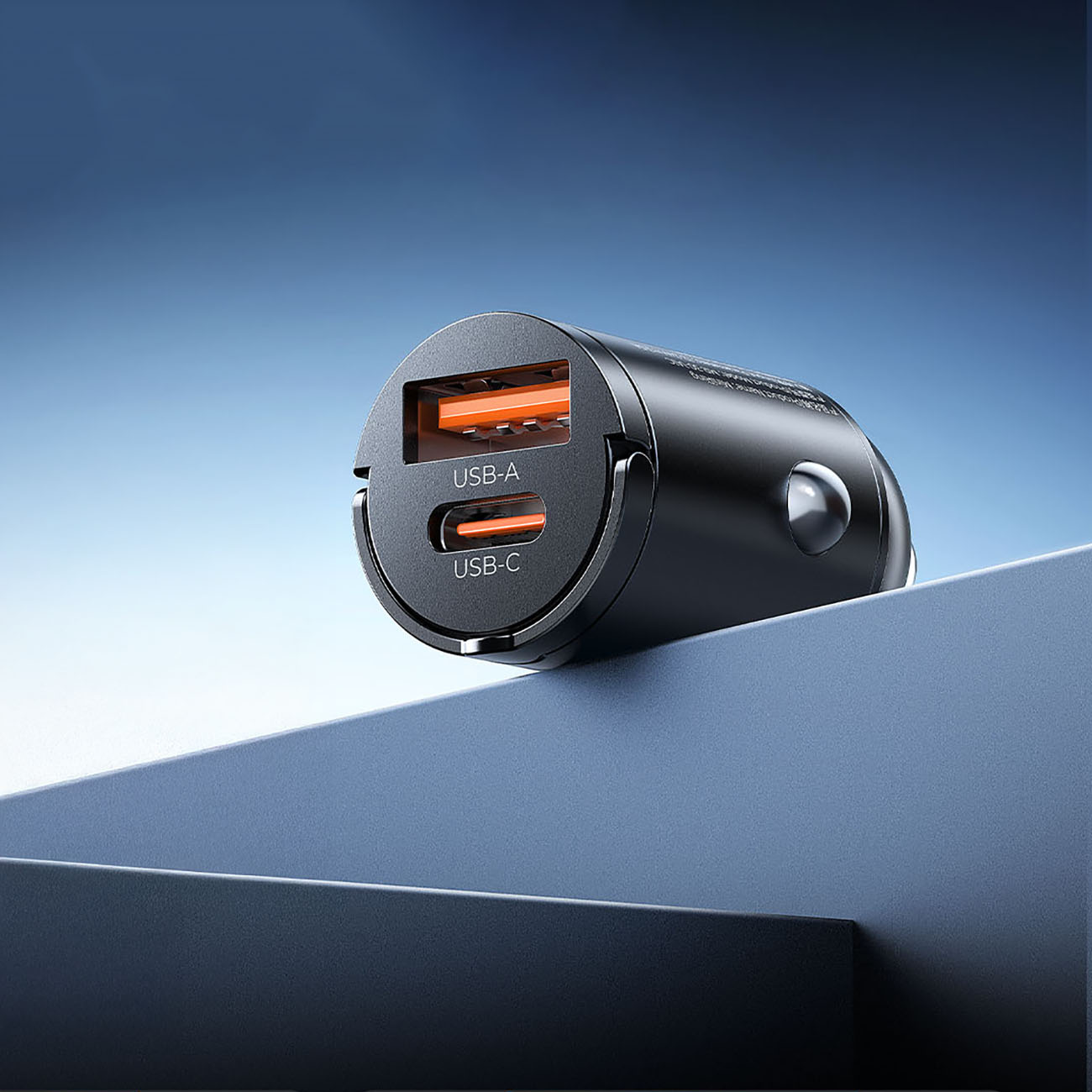 Czarna ładowarka samochodowa z portami USB-A i USB-C, pomarańczowymi akcentami, na niebieskim tle.
