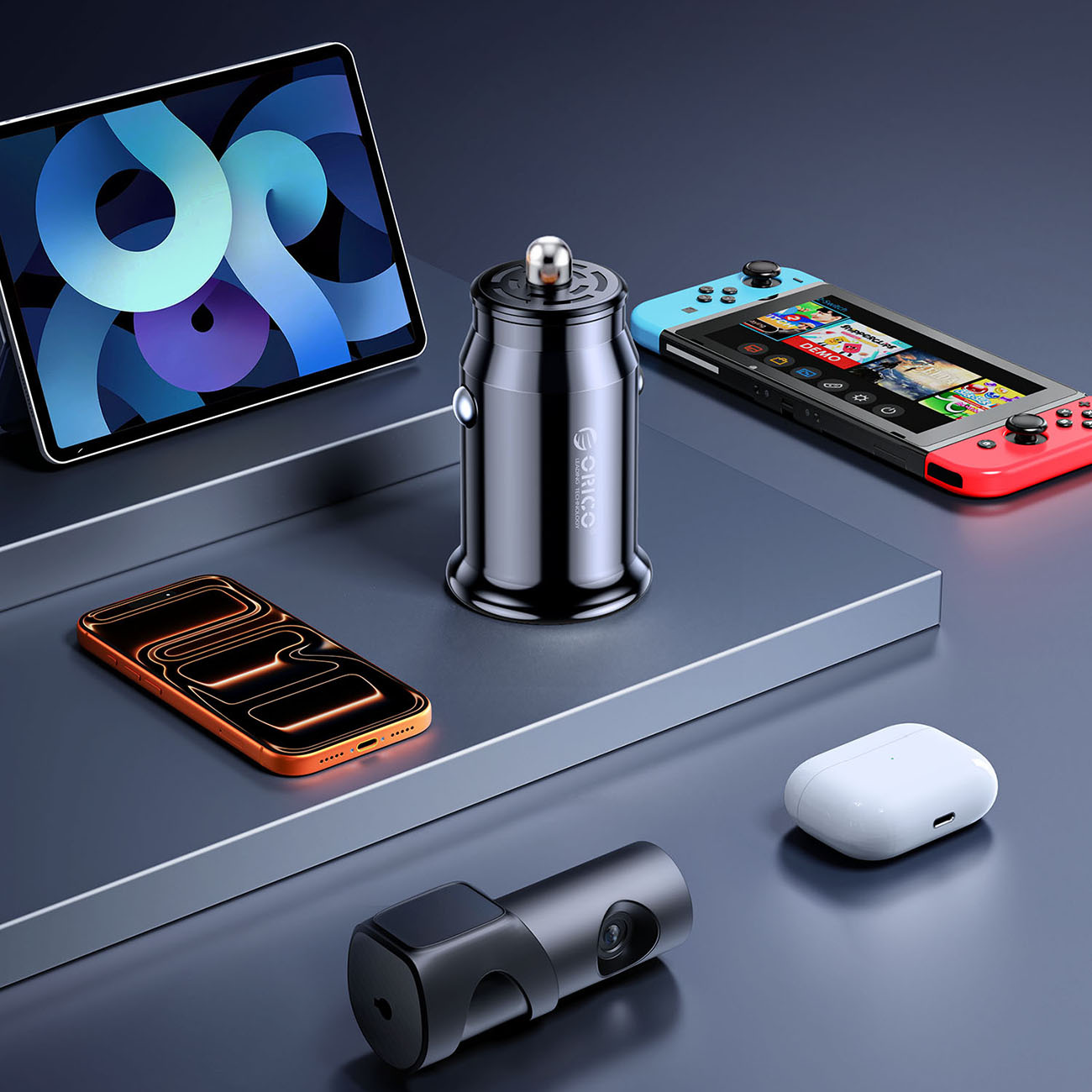 Tablet, ładowarka samochodowa, telefon, Nintendo Switch, kamera samochodowa i etui na słuchawki na ciemnej powierzchni.