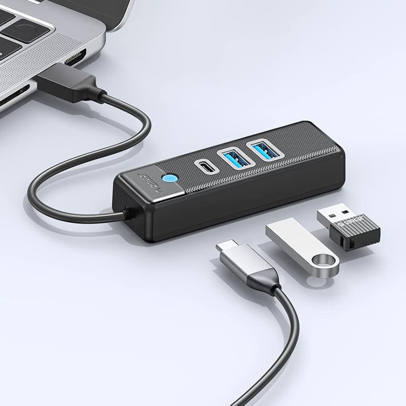 Czarny hub USB podłączony do laptopa, w pobliżu pendrive'y.