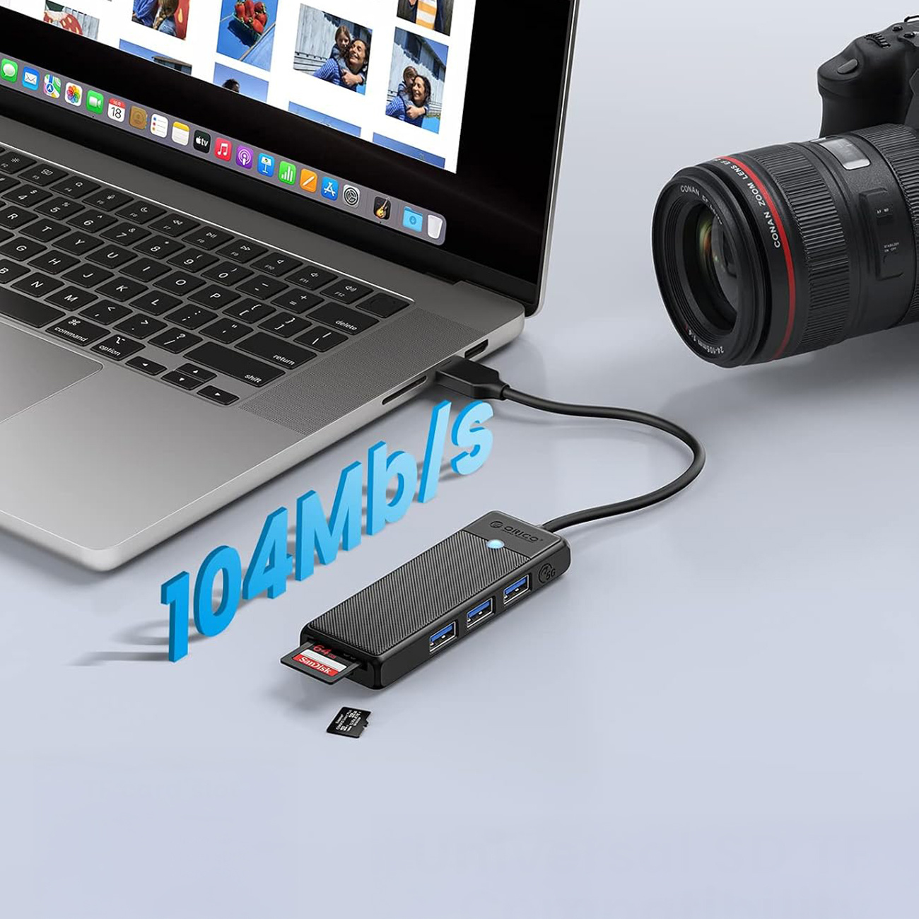 Laptop podłączony do huba USB z kartą SD. Obok znajduje się aparat.