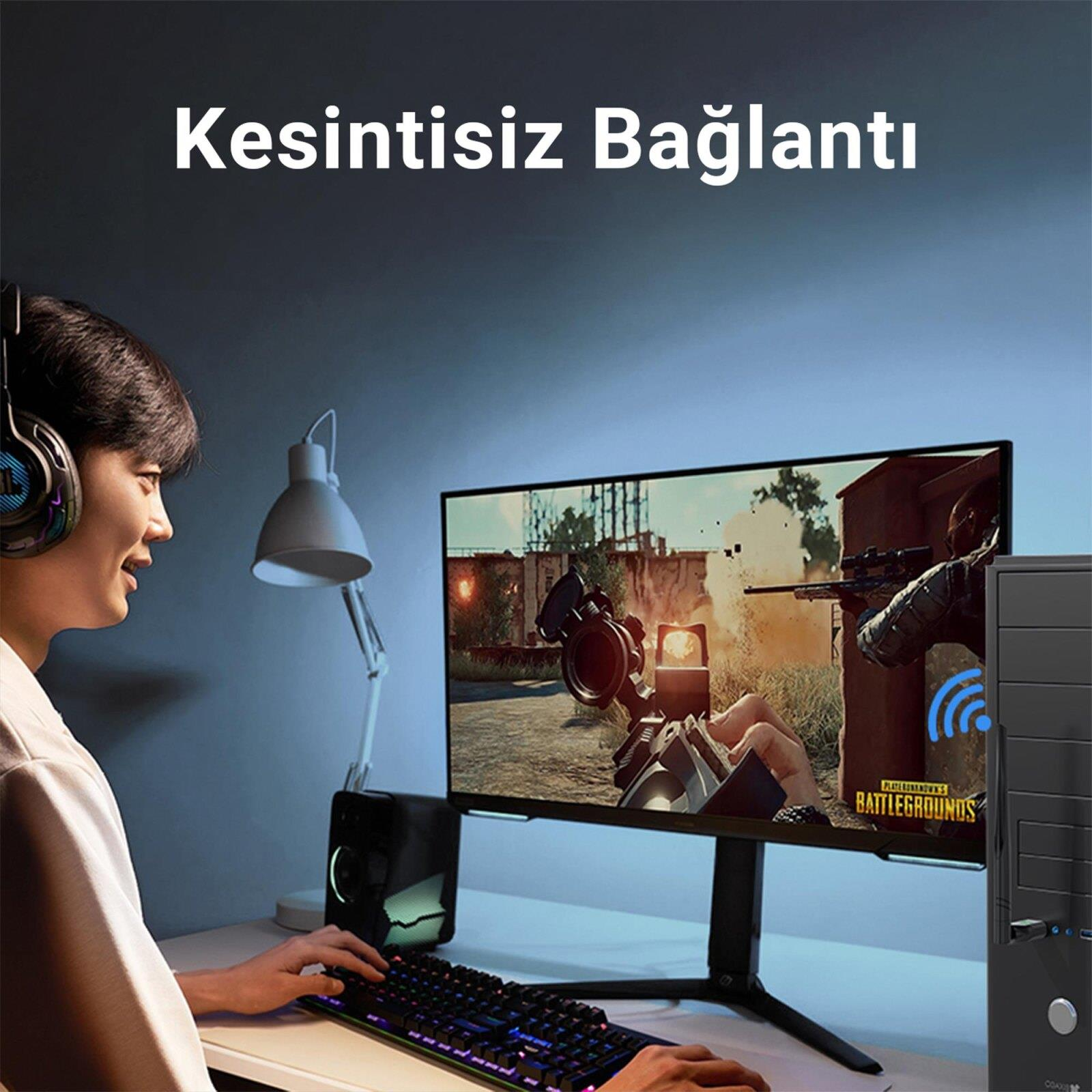 Kulaklıklı bir kişi, yanında bir bilgisayar bulunan monitörde nişancı oyunu oynuyor.