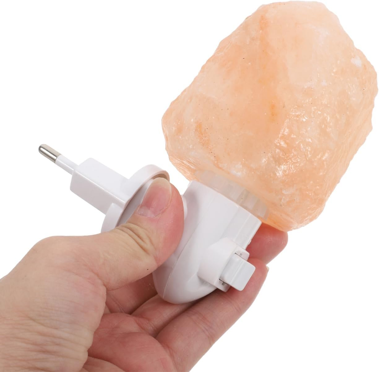 Eine Hand hält einen weißen Stecker mit einer rosa Salzkristalllampe.
