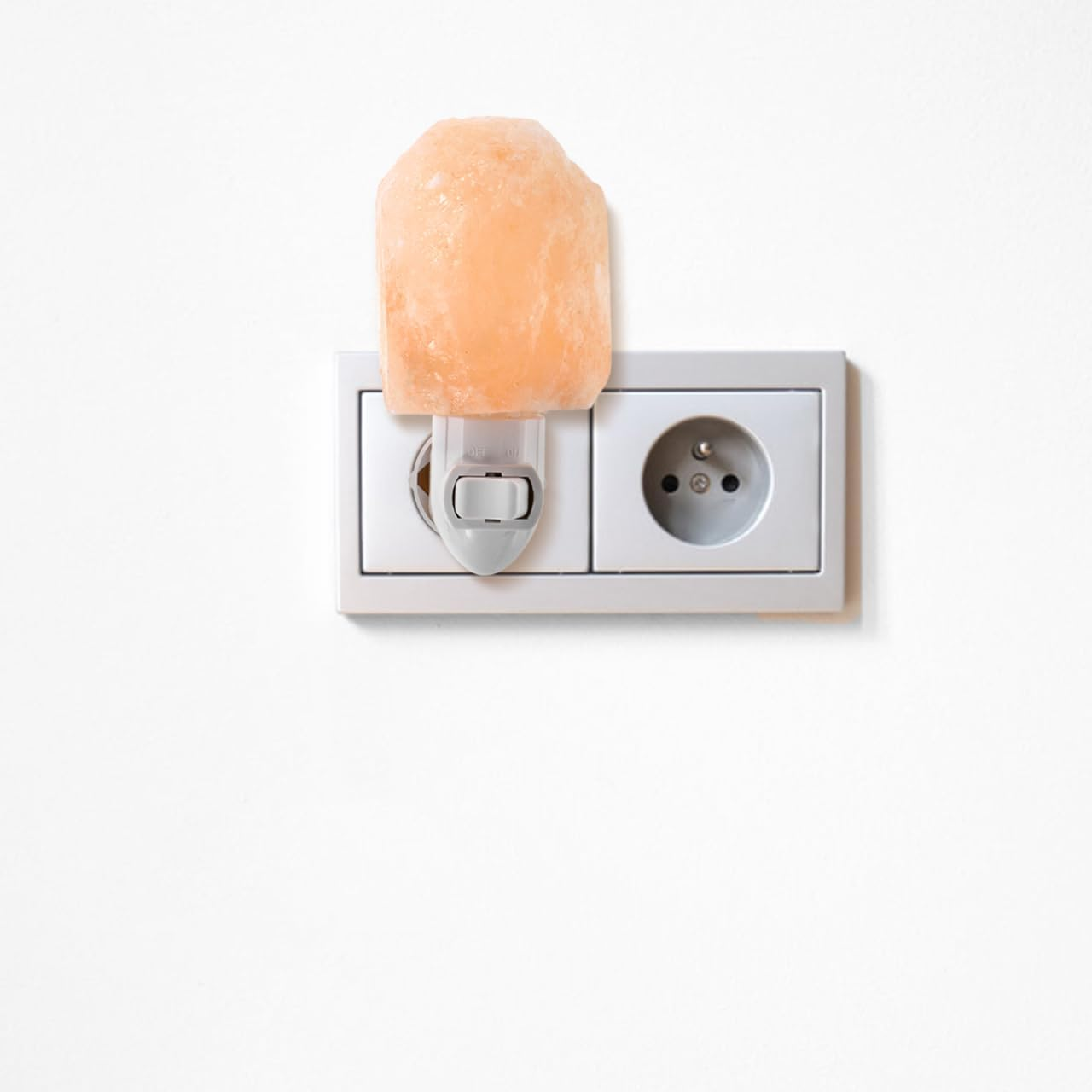 Ein orangefarbener Salzlampen-Nachtlichtstecker in einer weißen Steckdose.