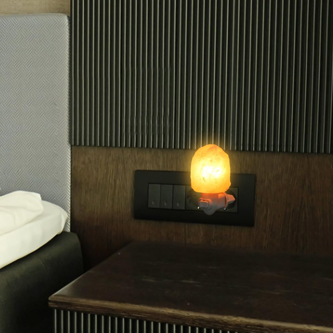 Eine Himalaya-Salzlampe steckt in einer Steckdose und strahlt ein warmes orangefarbenes Licht aus.