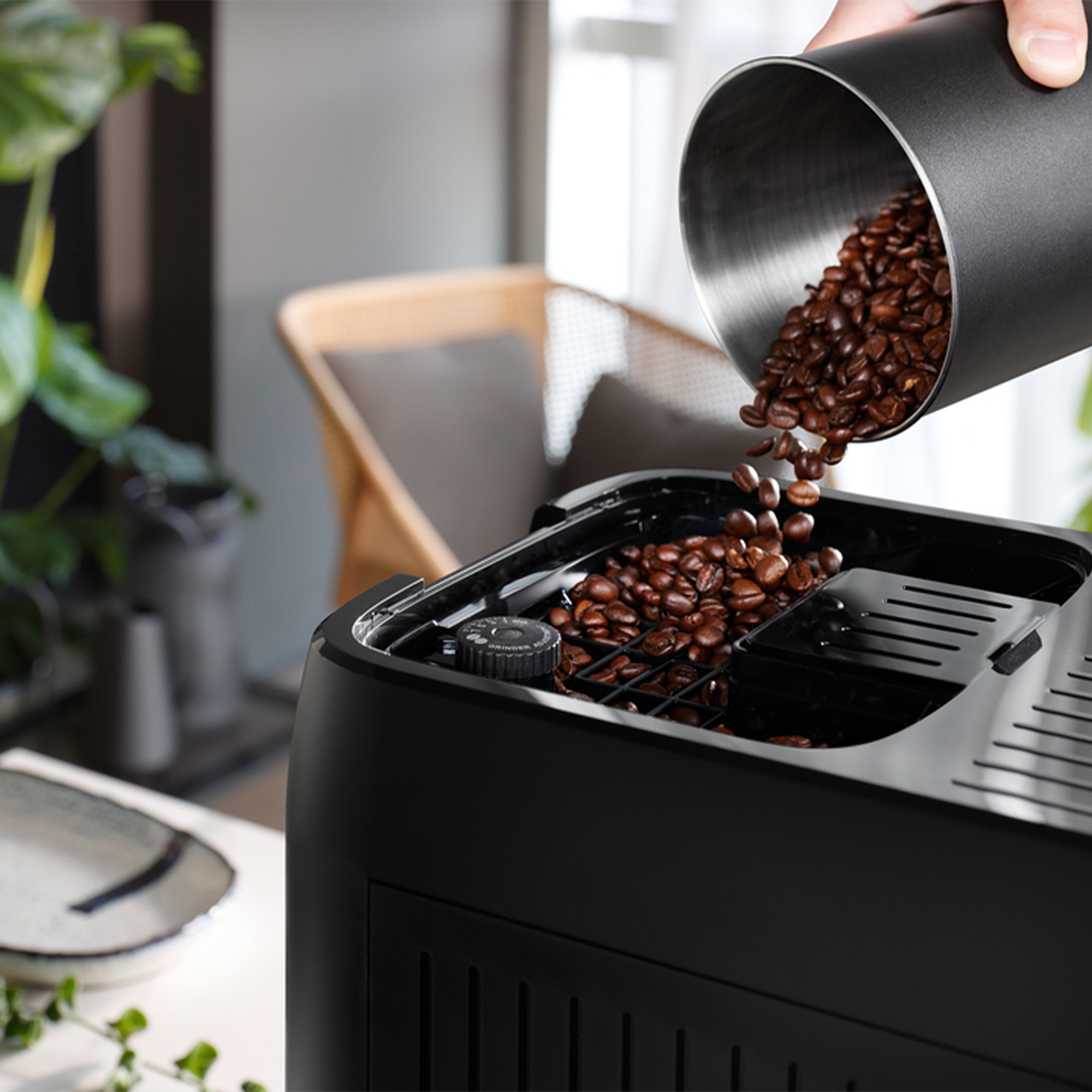 I chicchi di caffè vengono versati da un contenitore di metallo in una macchina da caffè.