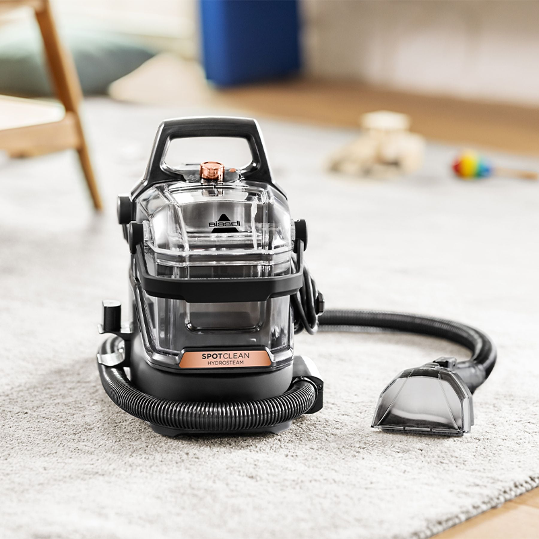 Pulitore per tappeti Bissell SpotClean HydroSteam nero e trasparente su un tappeto.