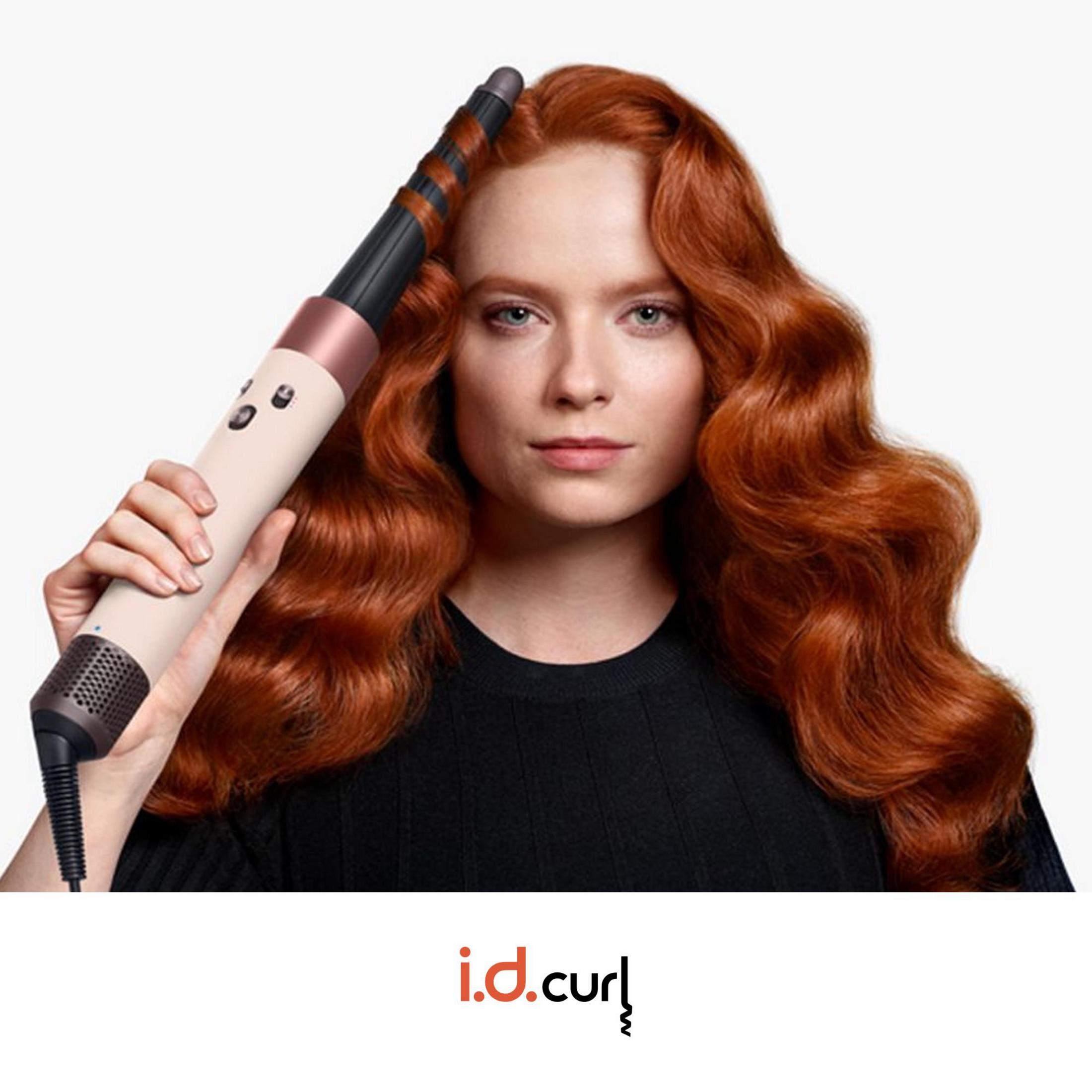 Donna con capelli rossi usa un arricciacapelli collegato a un cavo.