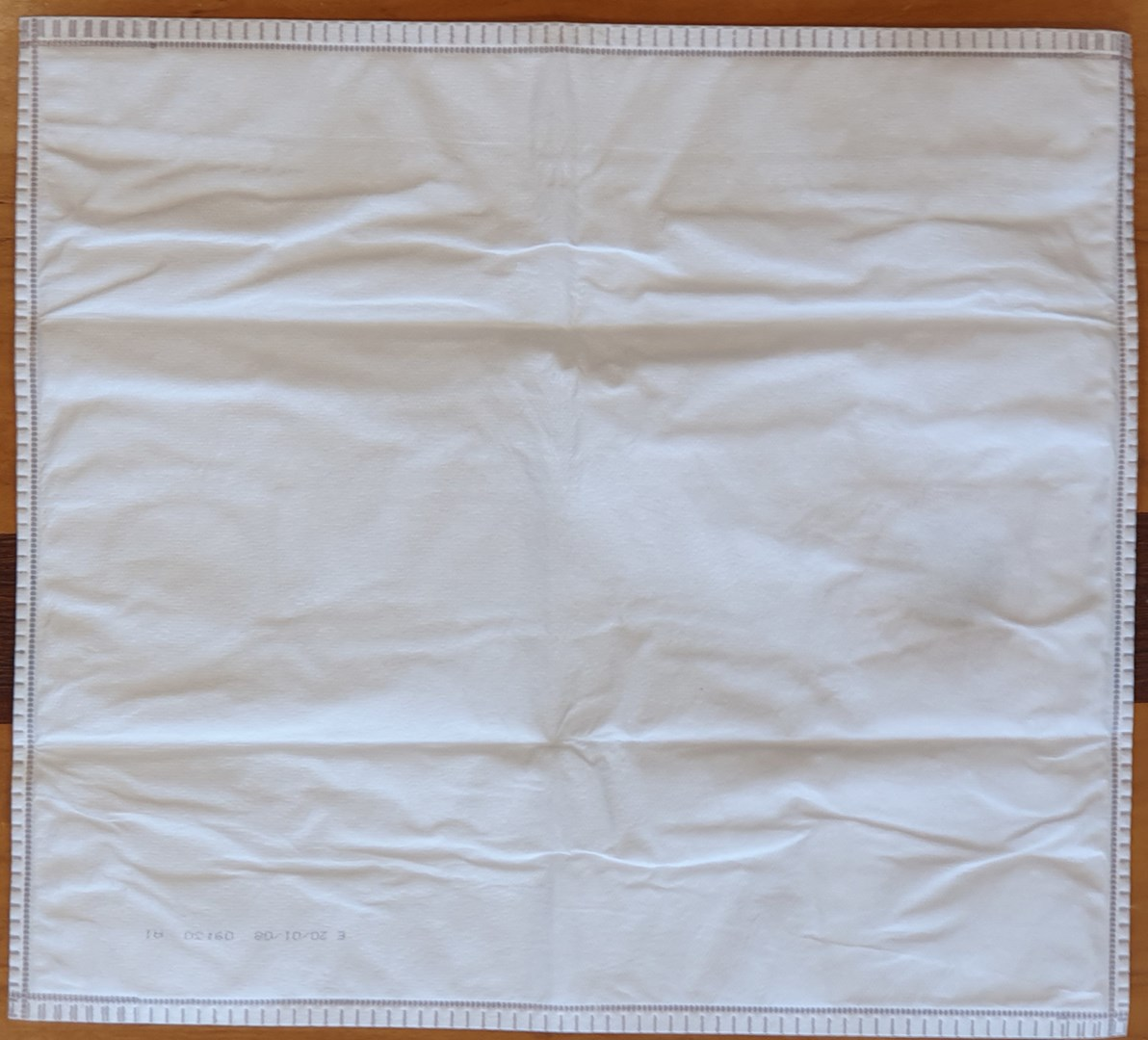 Un paño blanco plegado con costuras grises y estampado.