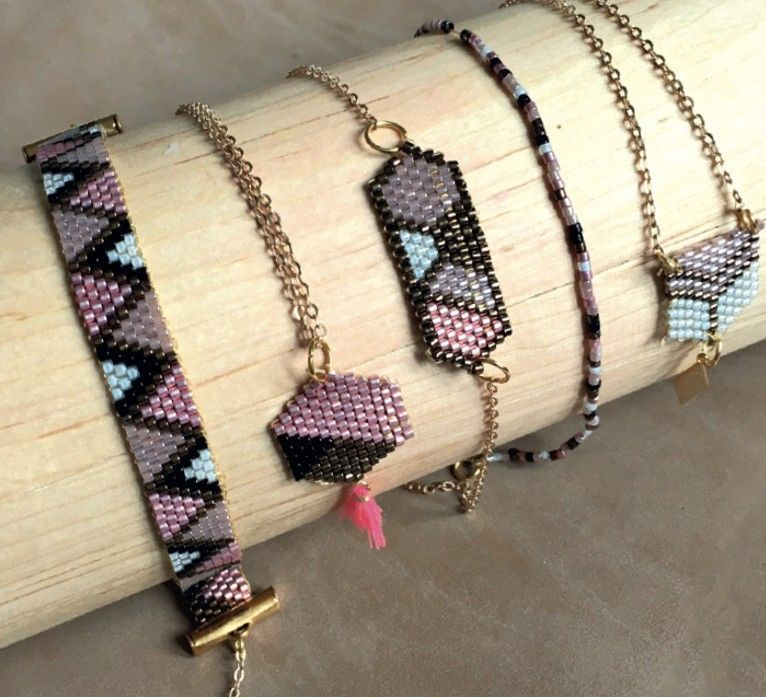Pulseras de cuentas rosas, negras y blancas, expuestas en un palo de madera.