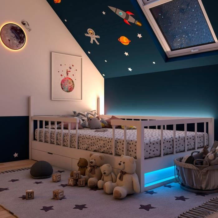 Stanza per bambini con letto, orsacchiotti e decorazioni a tema spaziale sul soffitto.