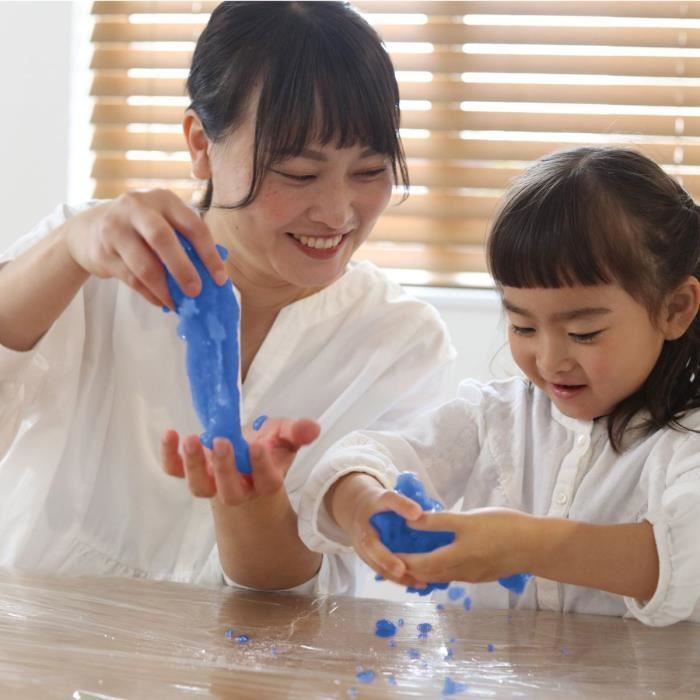 Una mujer y un niño juegan con plastilina azul sobre una mesa.