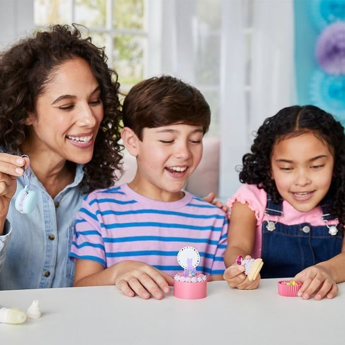 Una mujer y dos niños juegan con pequeños pastelitos de juguete y una forma de macaron.