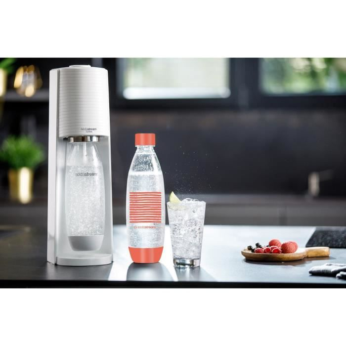 Una macchina SodaStream bianca a sinistra. Accanto, una bottiglia e un bicchiere di acqua frizzante con lime.