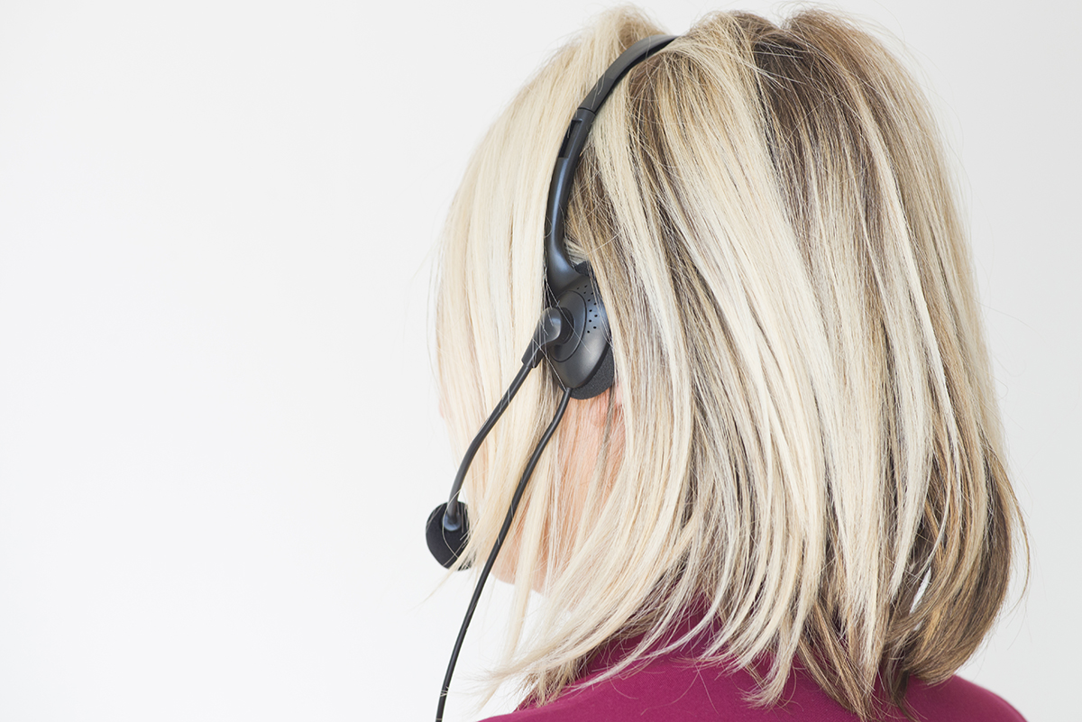 Una donna con capelli biondi indossa un auricolare con microfono.
