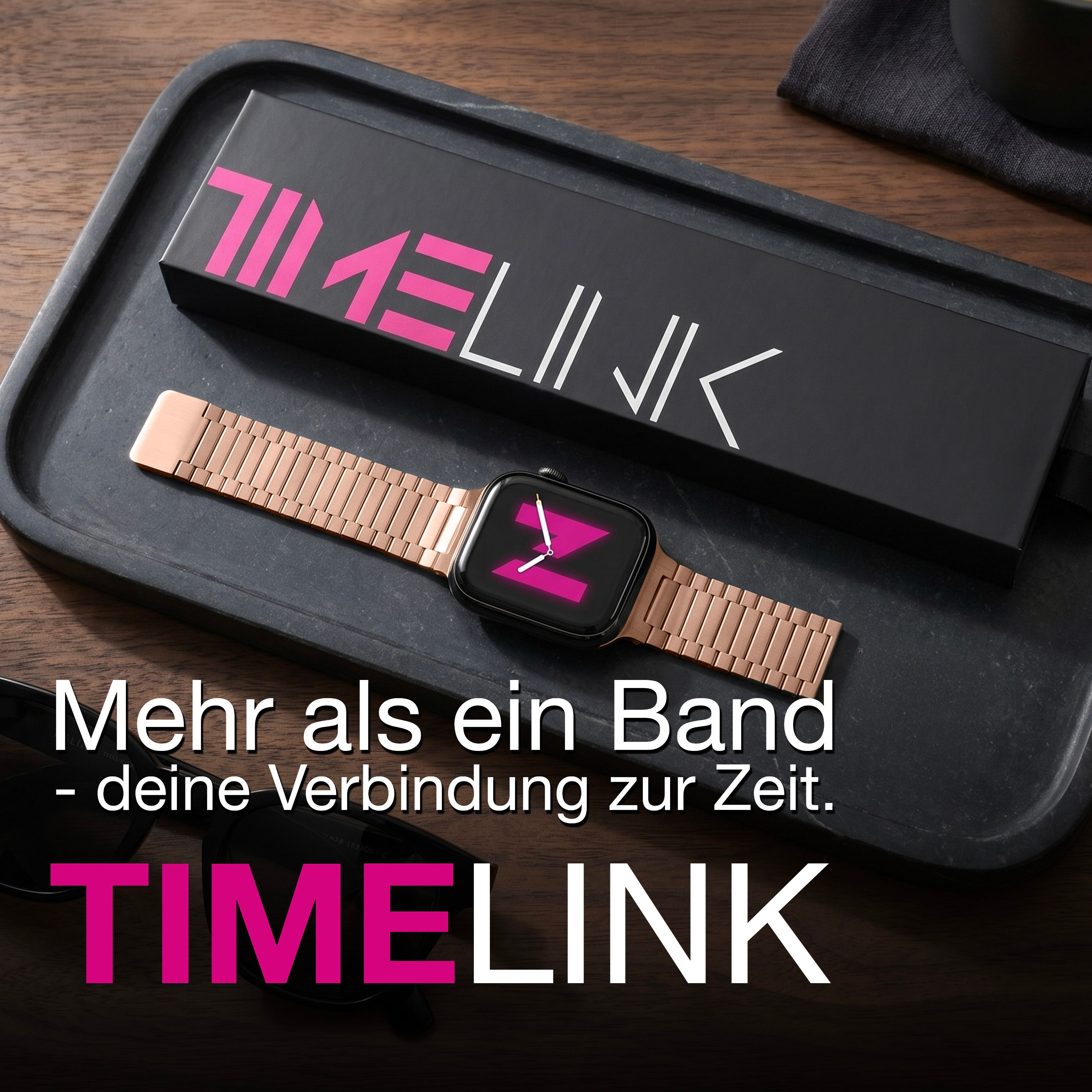 Smartwatch mit roséfarbenem Armband und schwarzer Box auf Holztisch.