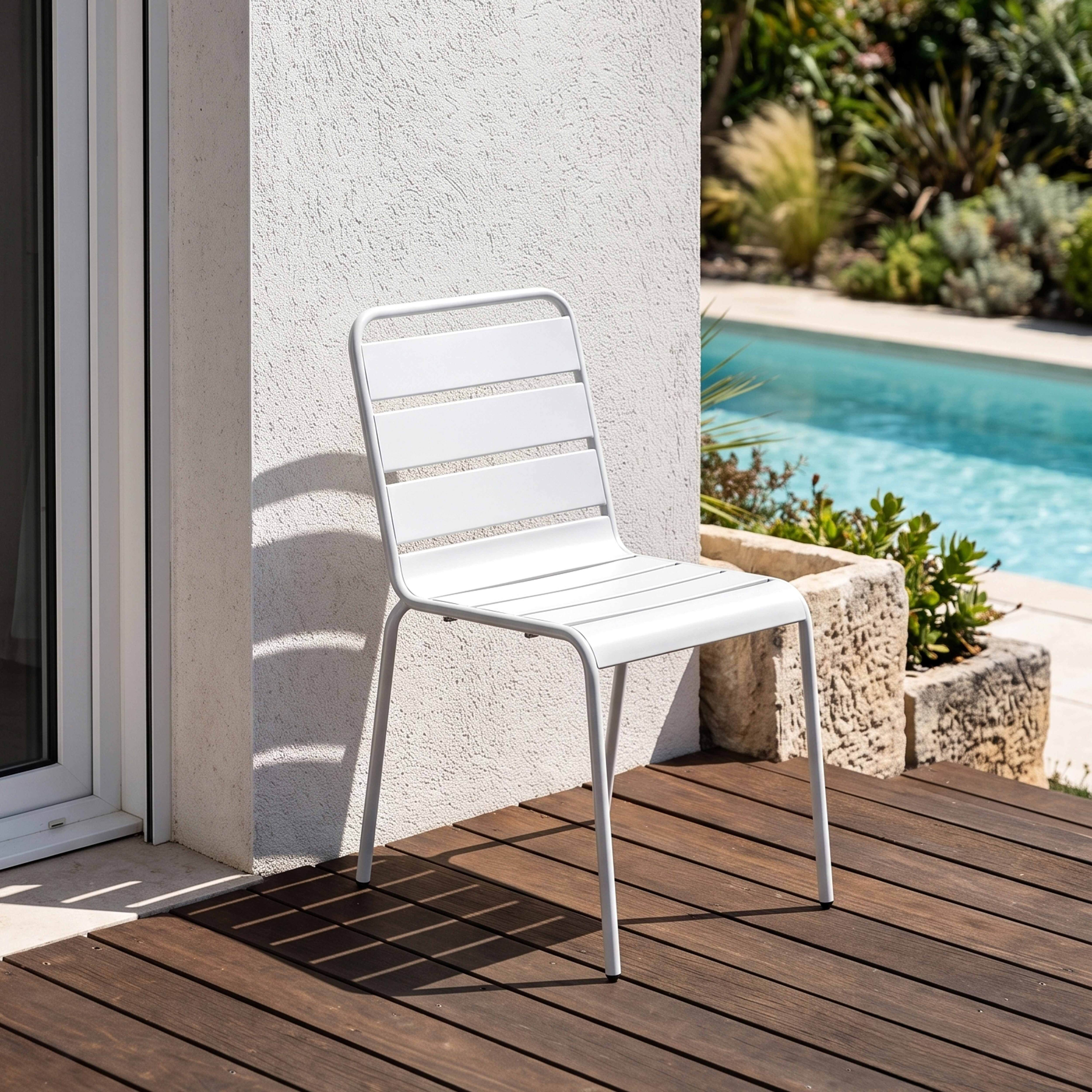 Ein weißer Stuhl steht auf einer Holzterrasse neben einem Pool.