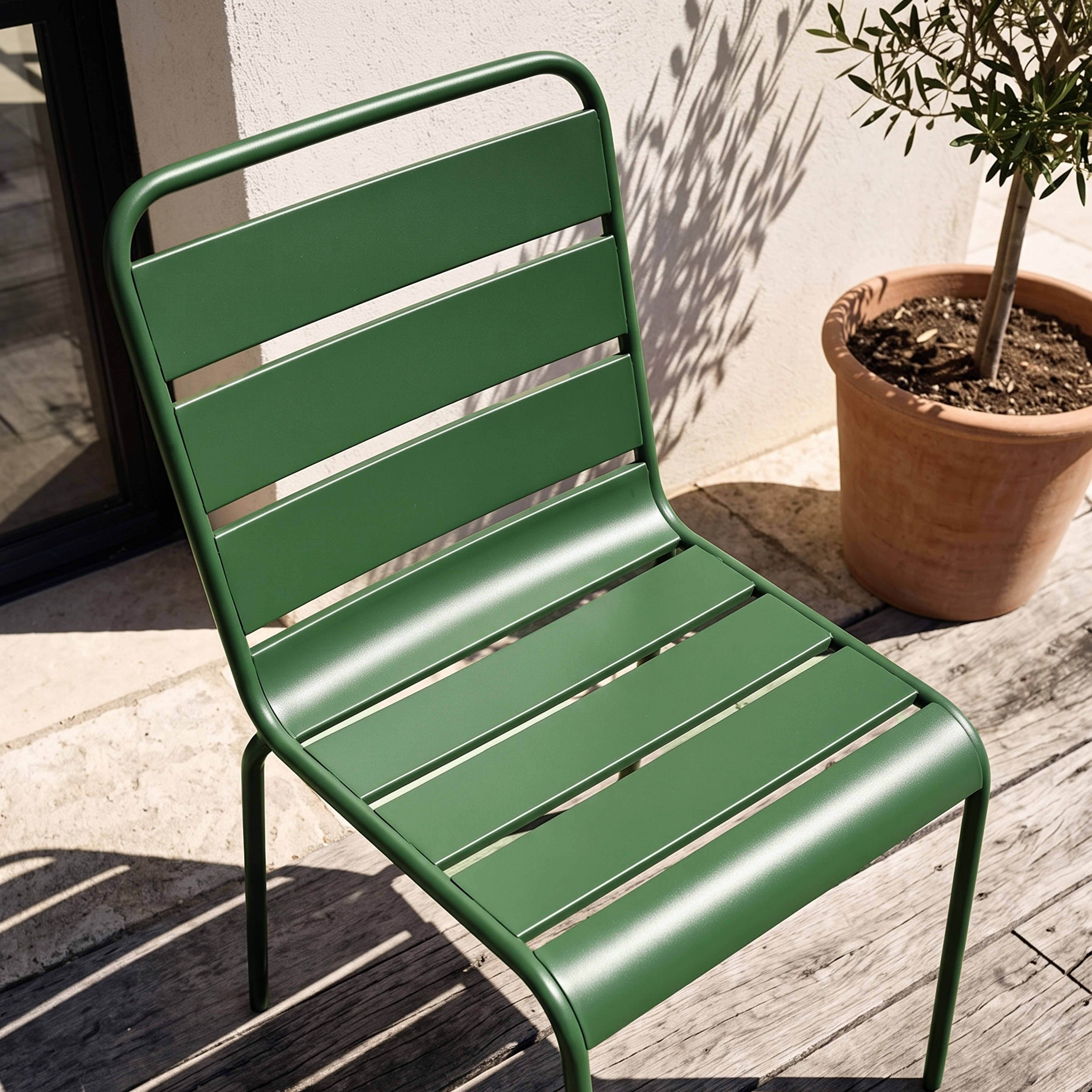 Grüner Metallstuhl auf Holzplanken mit Sonnenschatten und Topf.