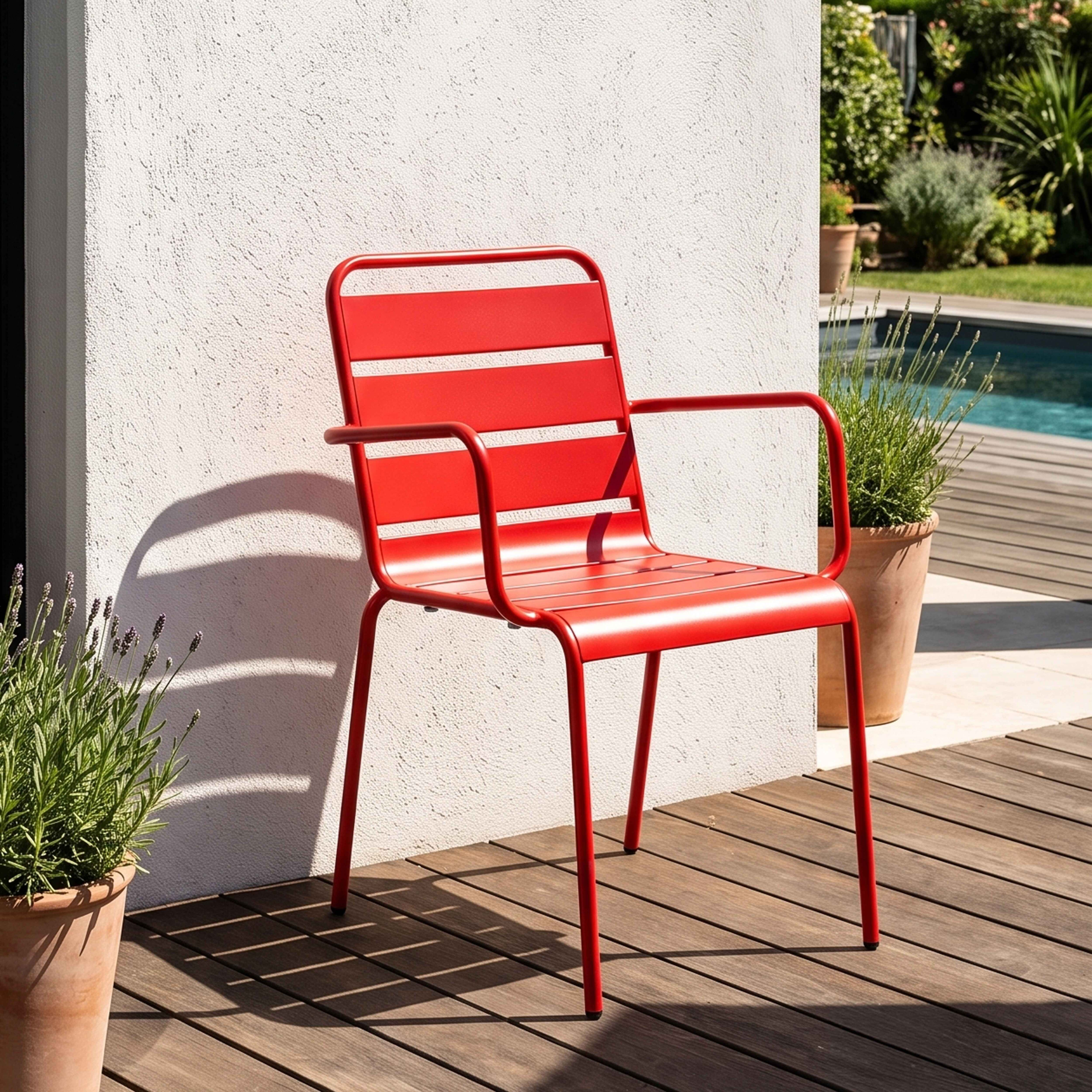 Ein roter Stuhl steht auf einer Holzterrasse neben einem Pool und Pflanzen.