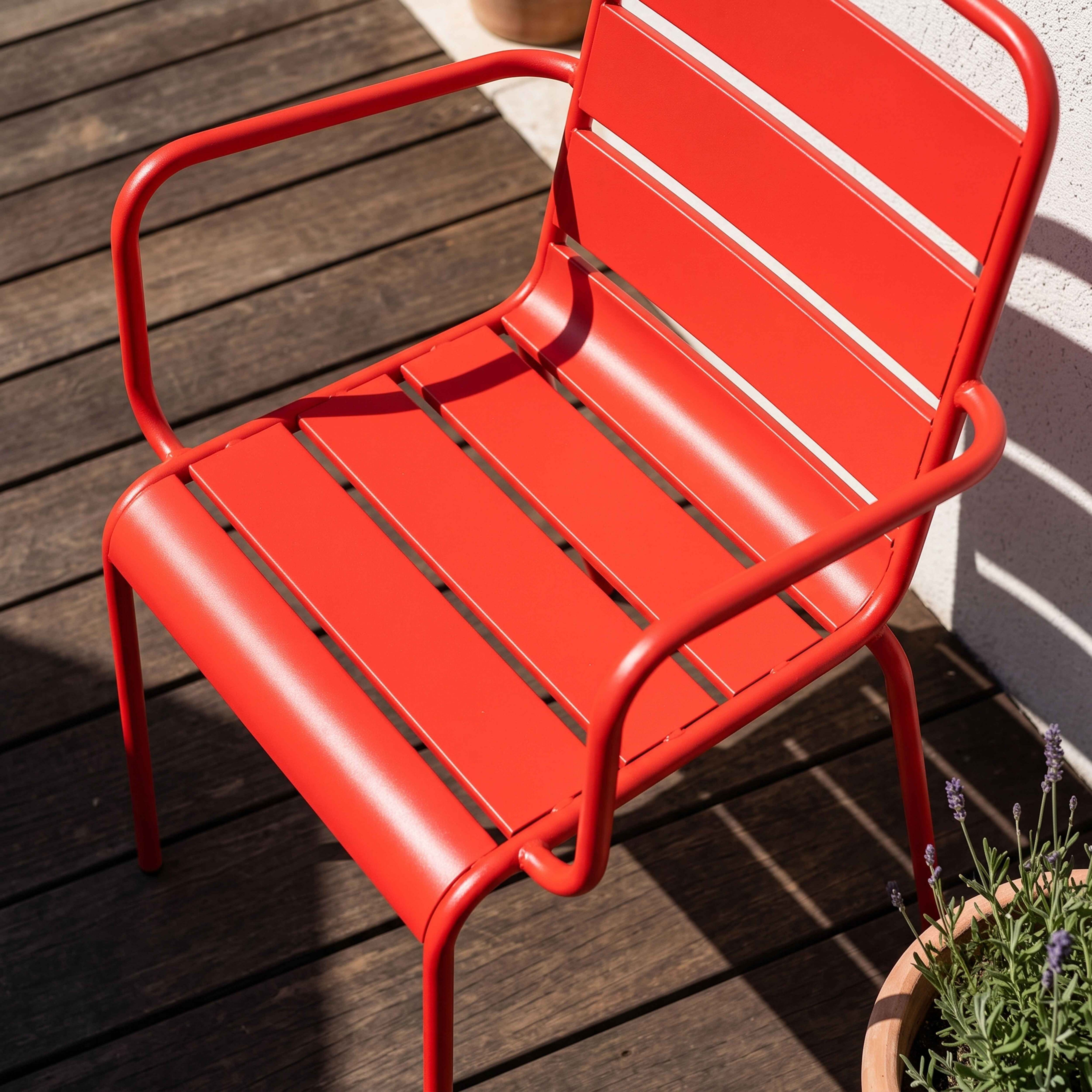 Ein leuchtend roter Stuhl aus Metall steht auf einer Holzterrasse.