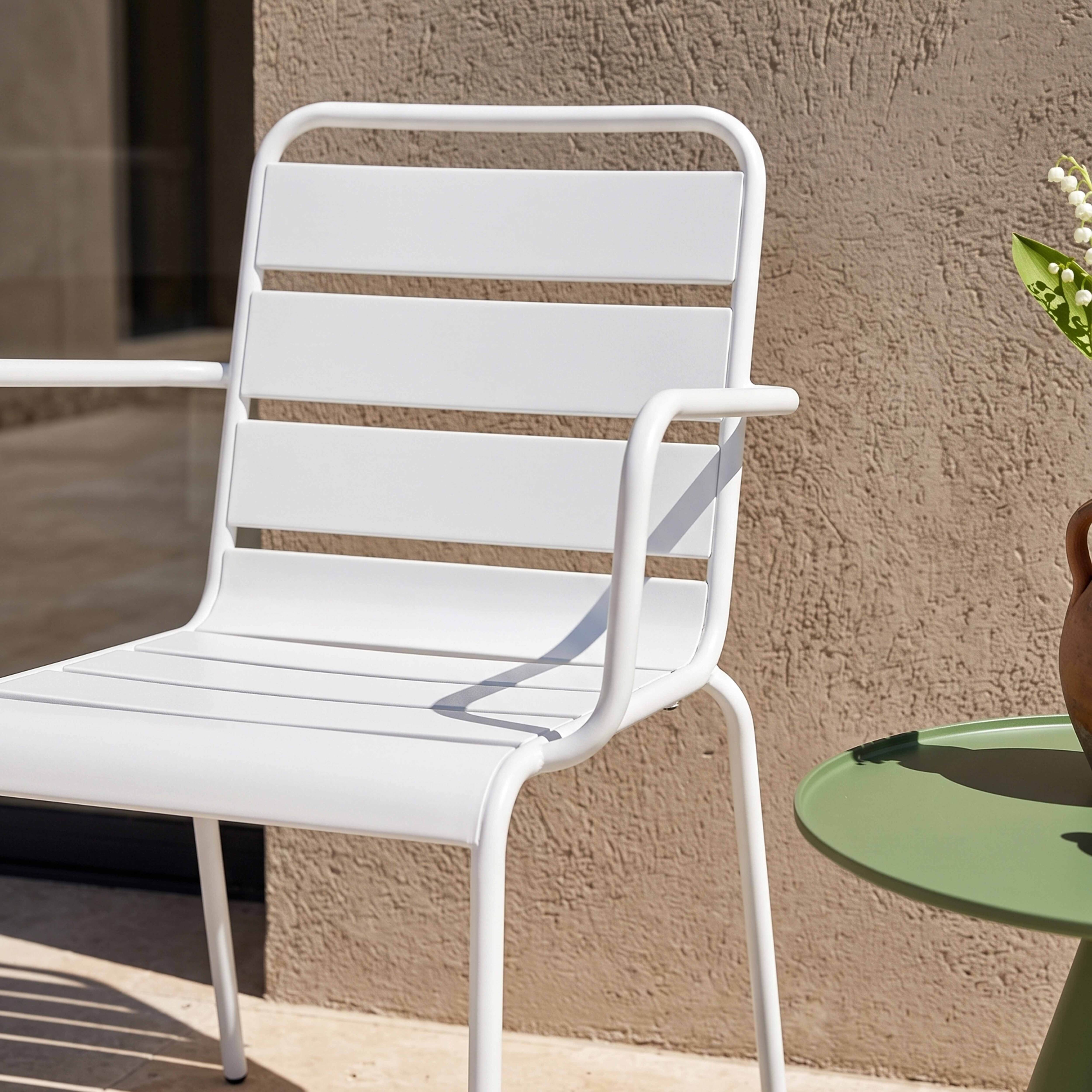 Weiße Gartenmöbel: Stuhl und runder Tisch mit Blumen.