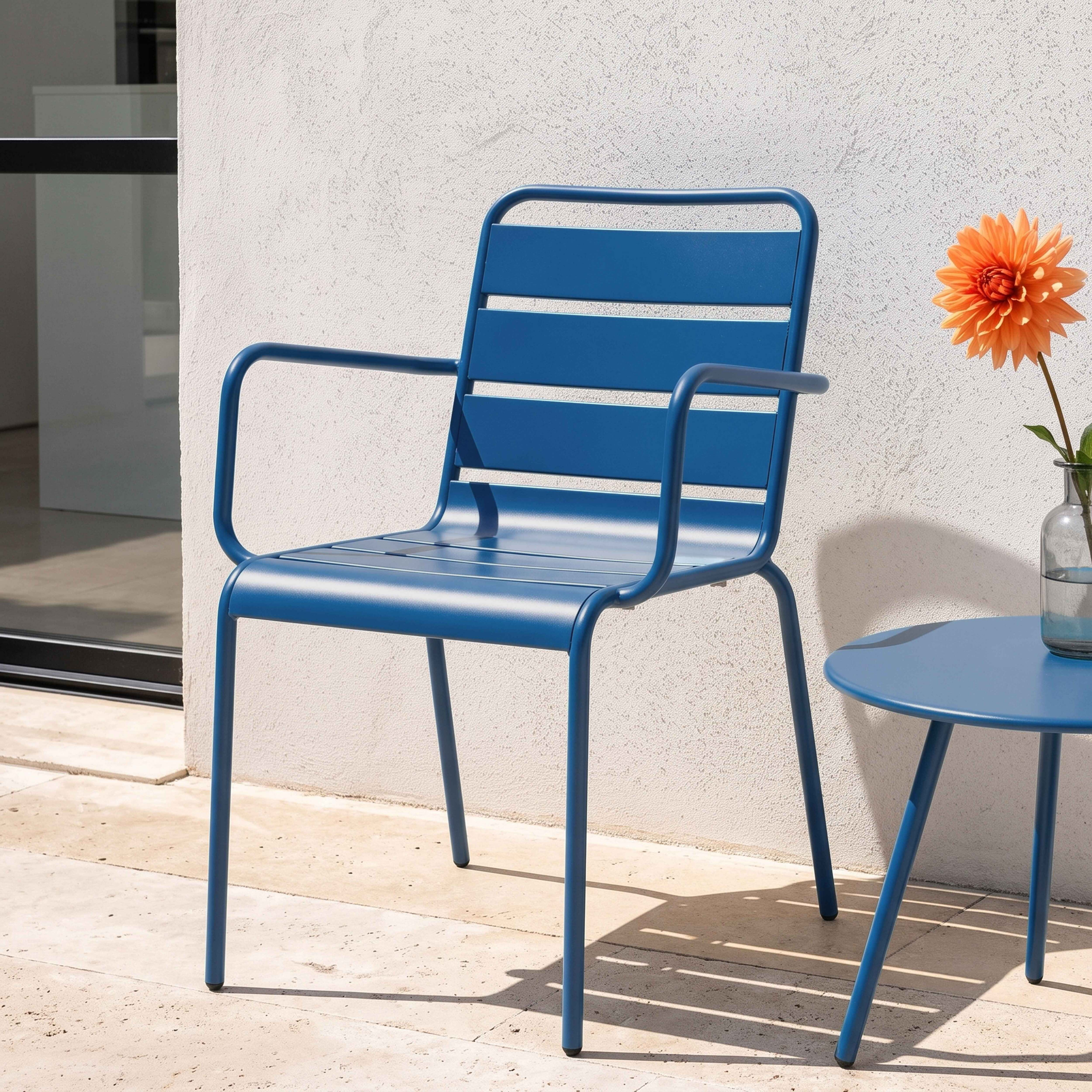 Ein blauer Stuhl und Tisch stehen auf einer Terrasse mit einer orangefarbenen Blume.