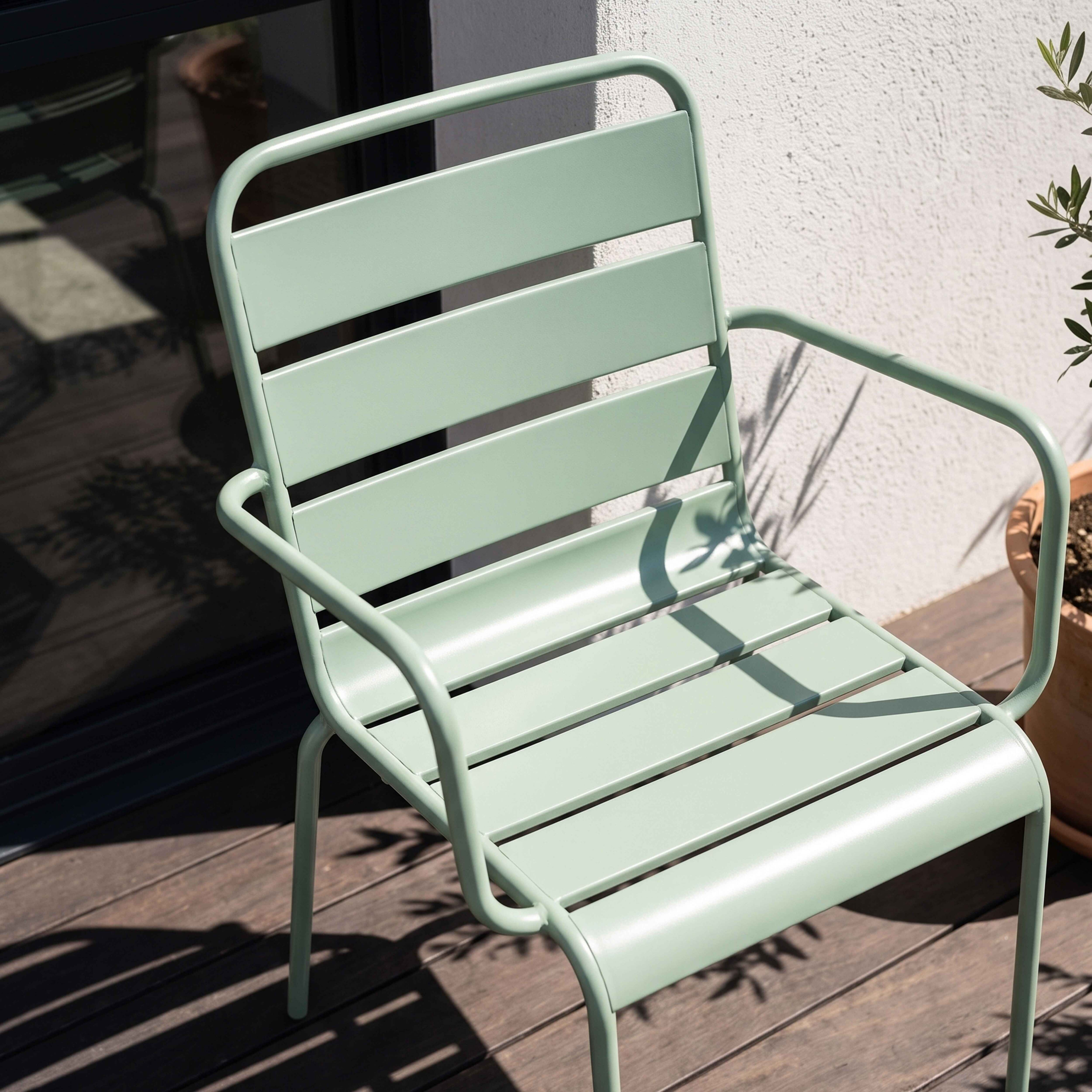 Eine hellgrüne Metallliege steht auf einer Holzterrasse im Schatten.