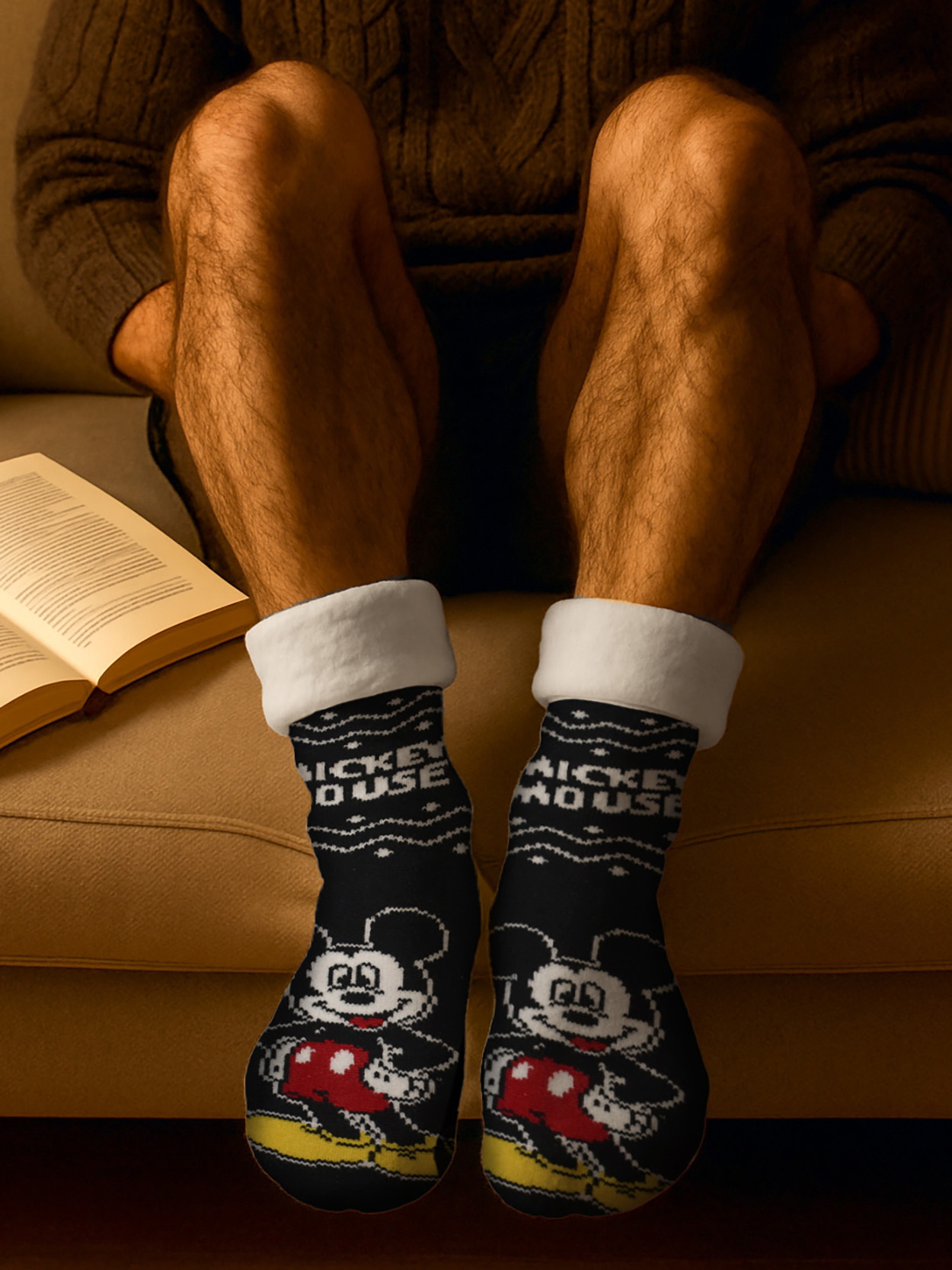 Ein Mann sitzt auf einer Couch und trägt Mickey Mouse Socken.