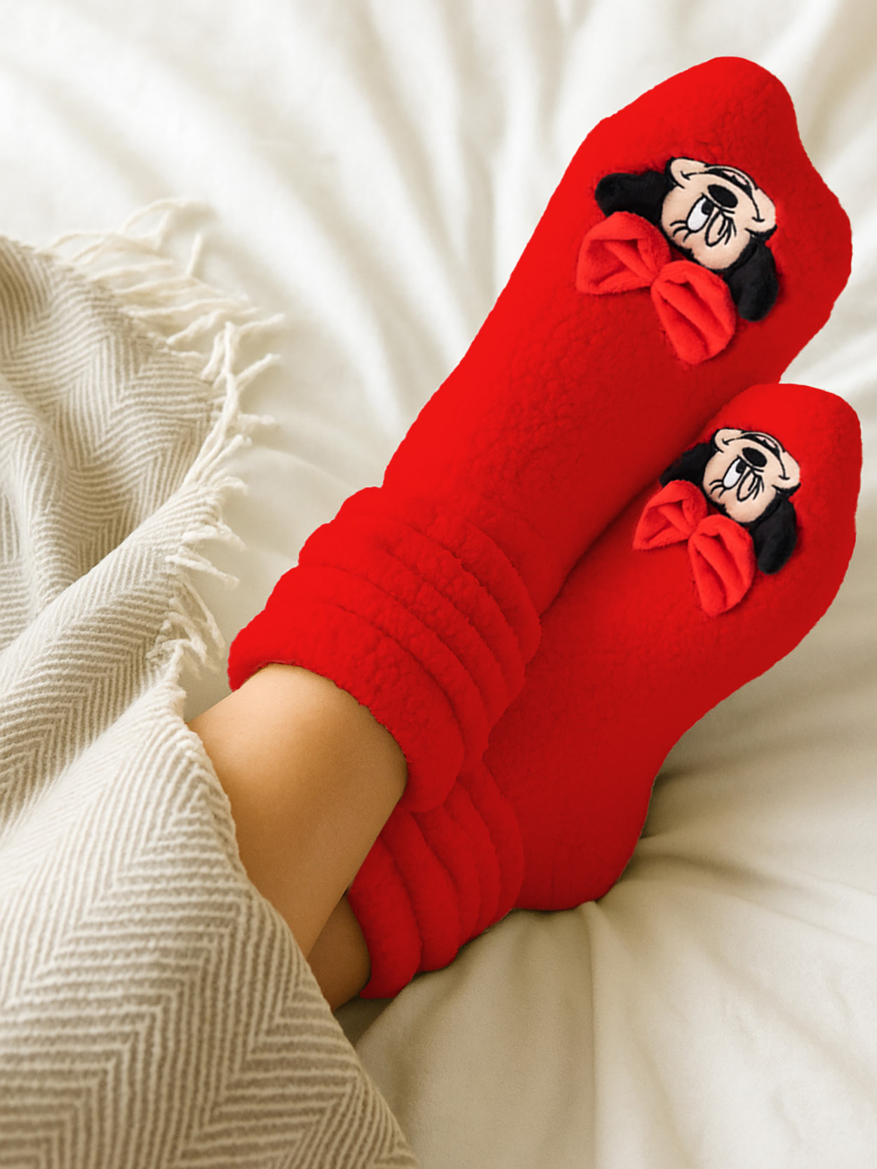 Füße in roten Socken mit Minnie-Maus-Motiv, unter einer Decke.