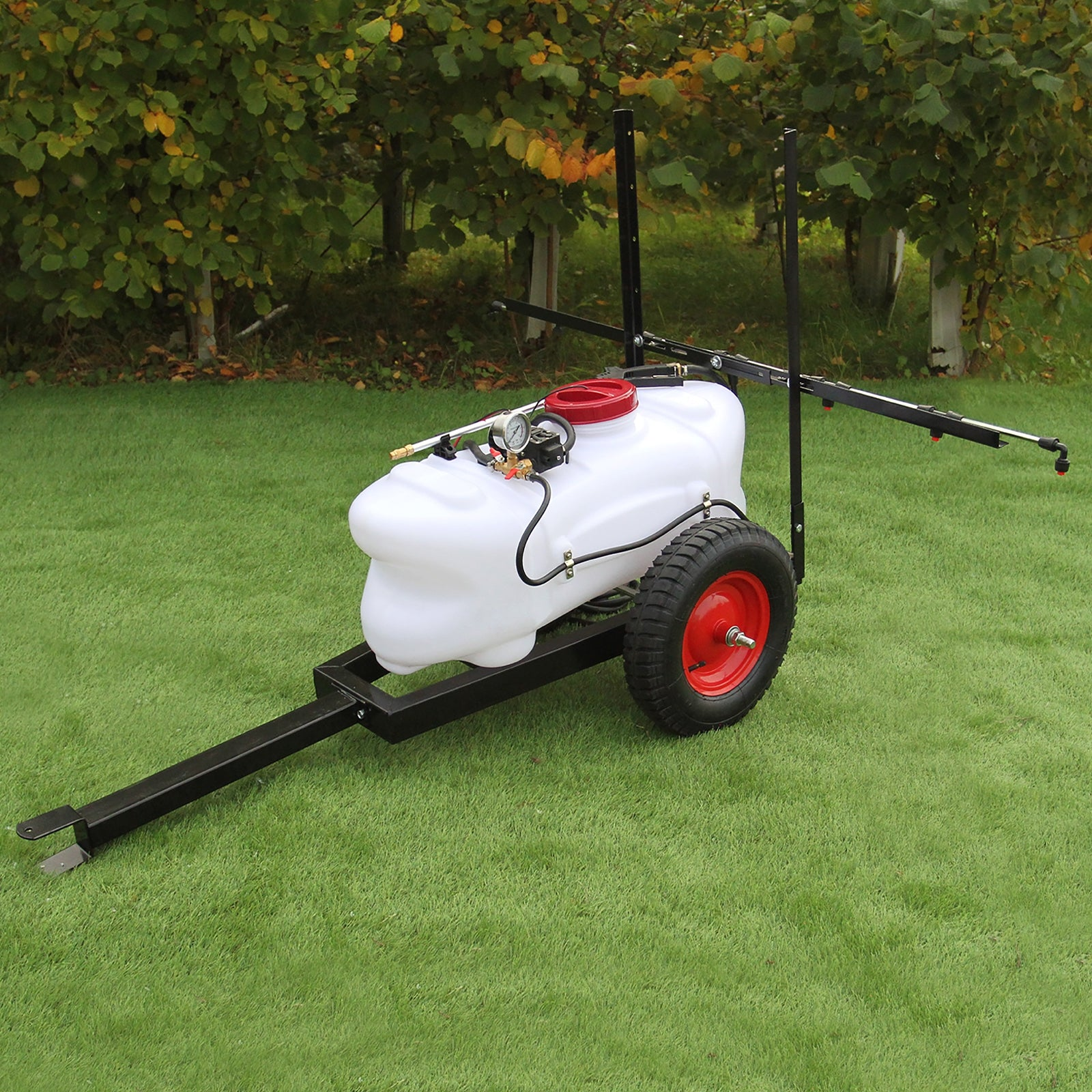 Un tanque rociador blanco en un remolque con rueda roja está sobre césped artificial.