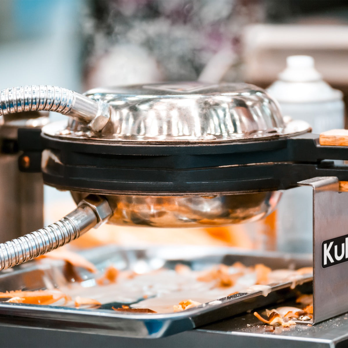 El vapor sale de una gofrera, con una bandeja de restos de comida debajo.