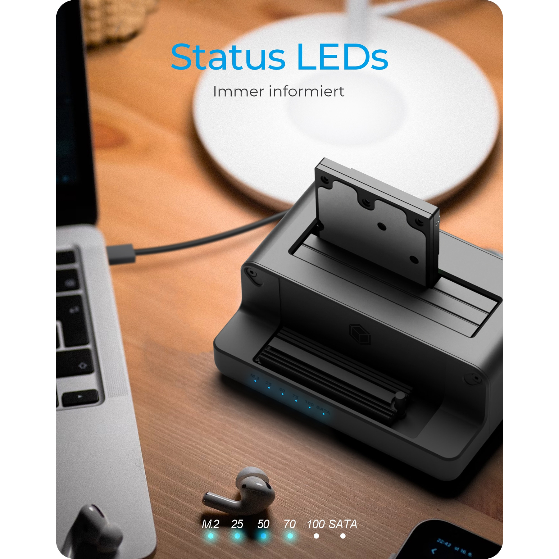 Station grise avec SSD, ordinateur portable et écouteurs sur table bois.