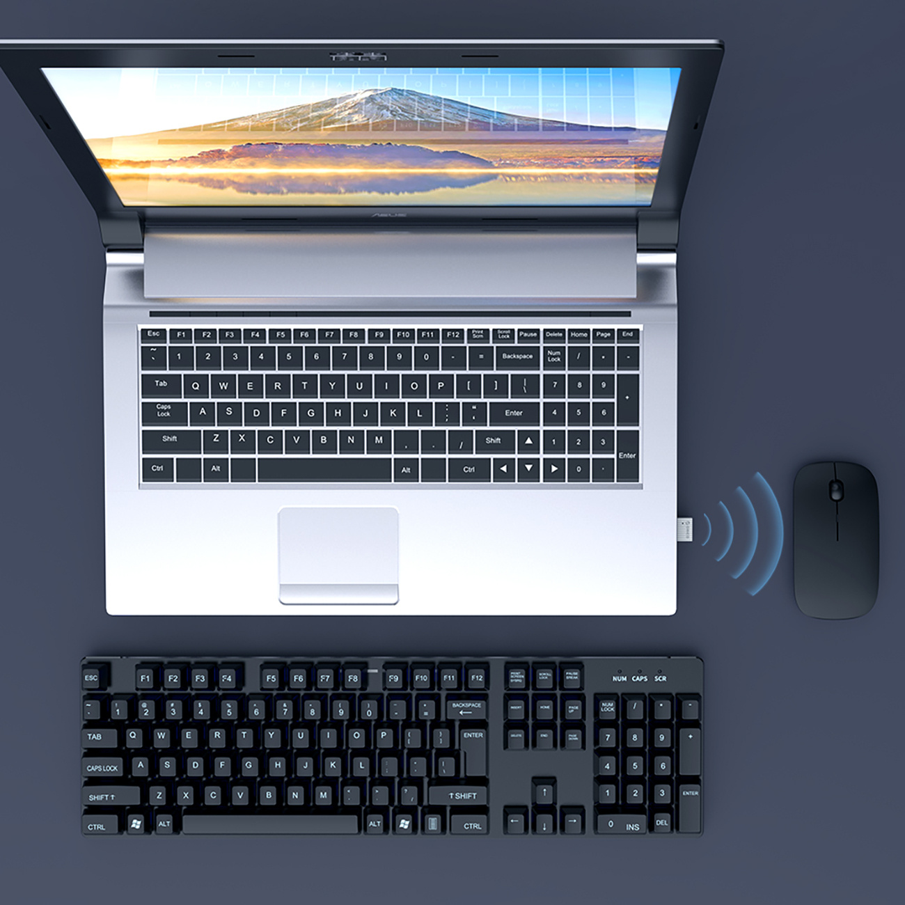 Laptop wyświetla krajobraz górski. W pobliżu znajdują się bezprzewodowa mysz i klawiatura.