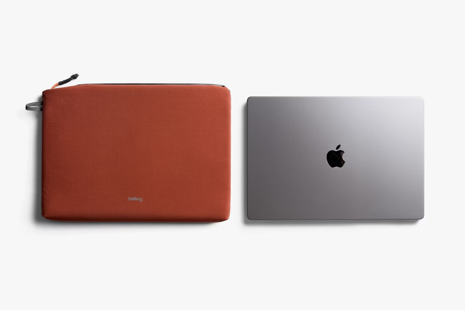 Pomarańczowa torba na laptop obok srebrnego MacBooka z logo Apple.