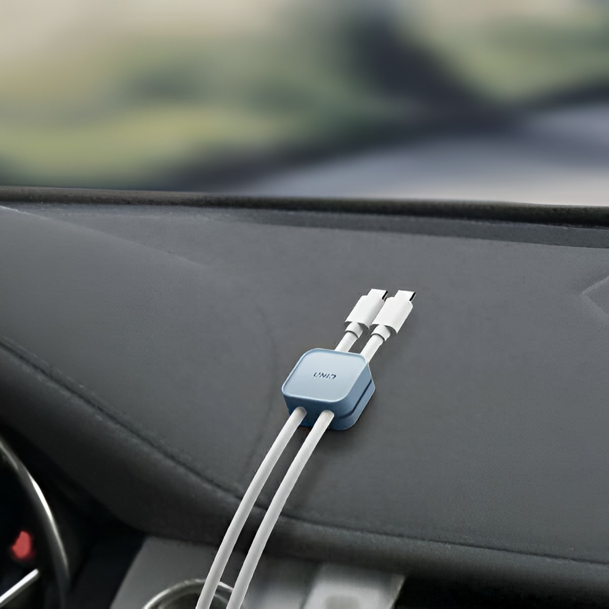 Niebieski uchwyt z dwoma białymi kablami USB-C na desce rozdzielczej.