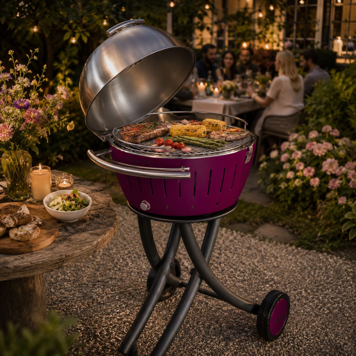 Fioletowy grill z gotującym się jedzeniem, w ogrodzie o zmierzchu z ludźmi jedzącymi kolację.