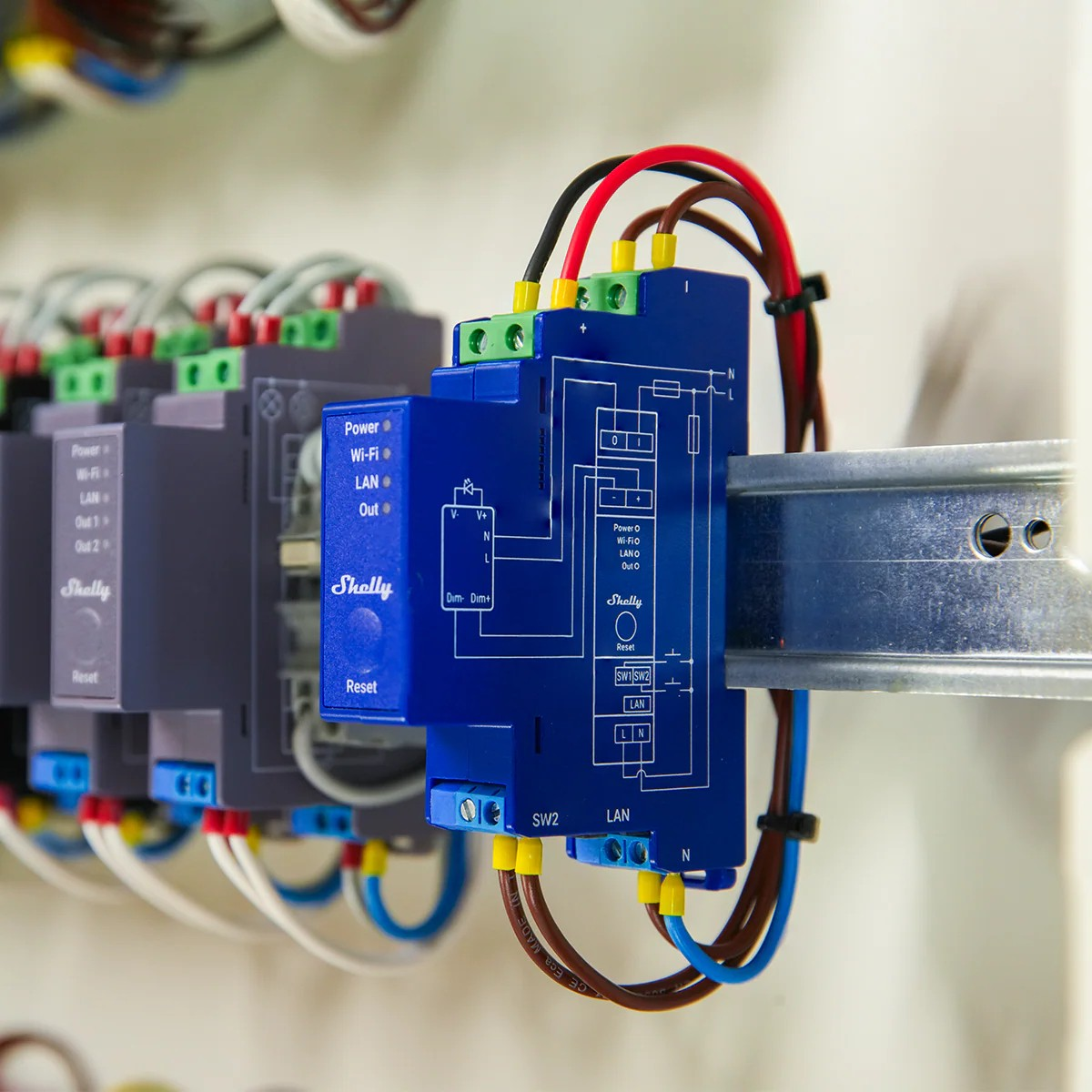 Moduli elettrici blu e grigi con cavi montati su una guida DIN.