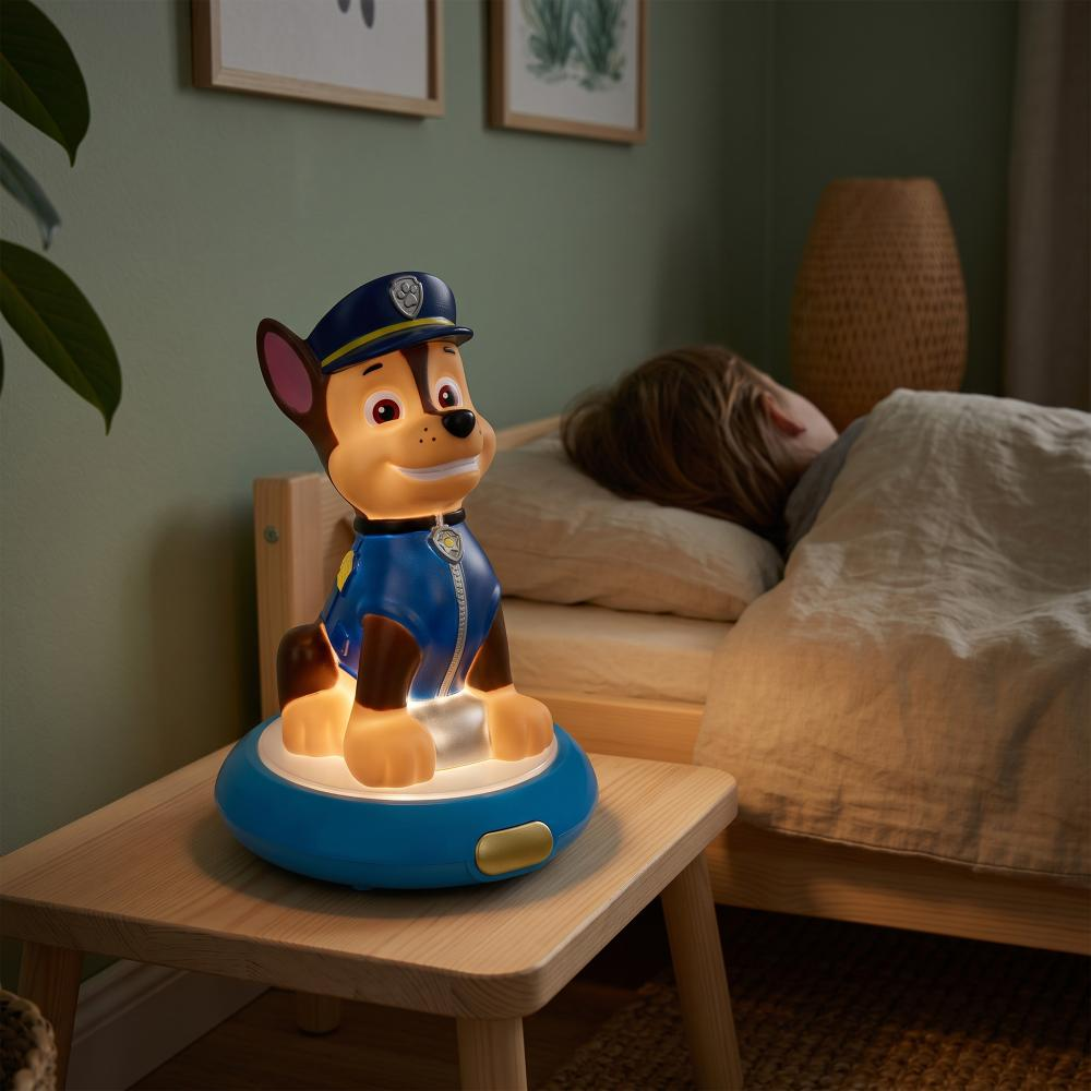 Lampka nocna Chase świeci na stoliku nocnym obok śpiącego dziecka.
