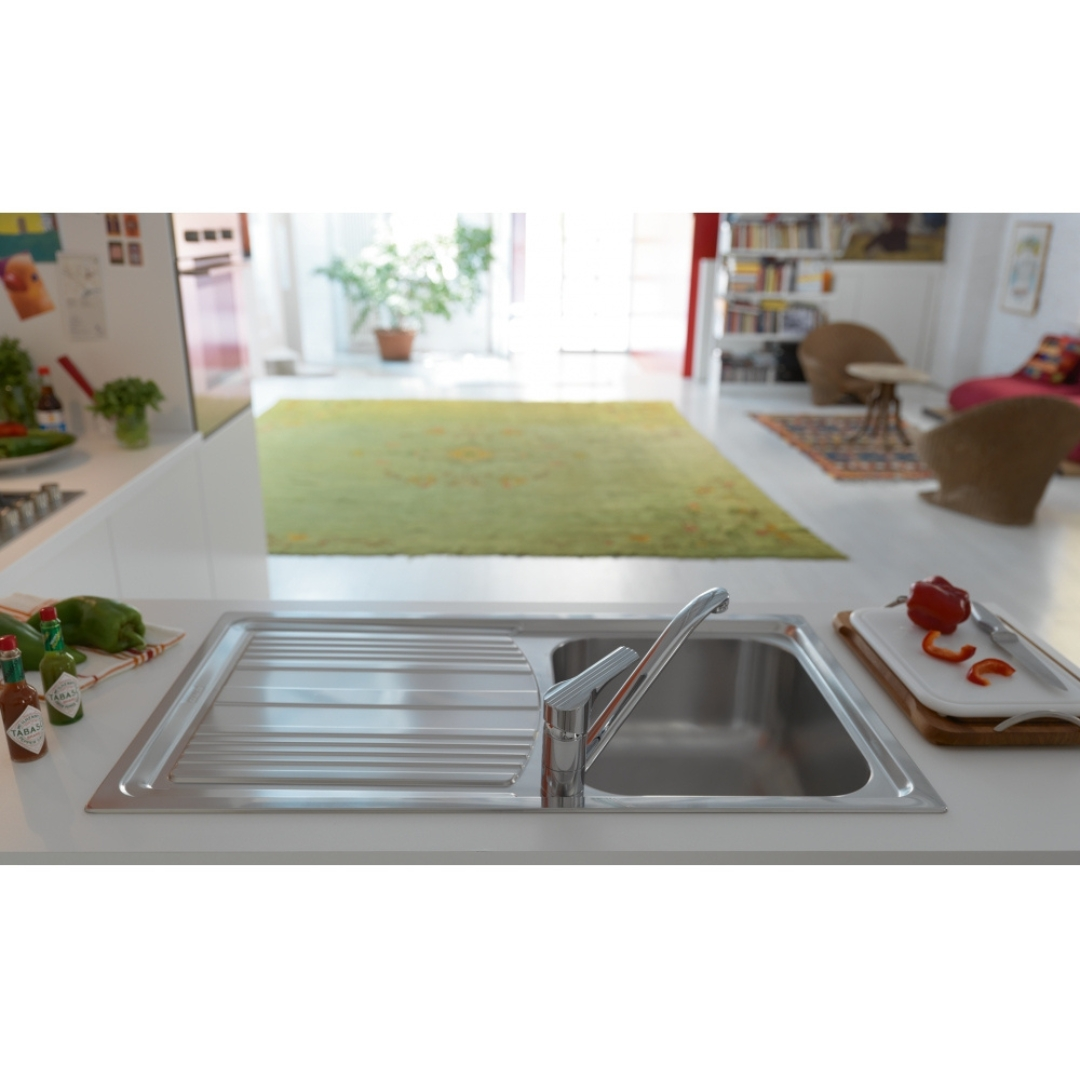 Un lavello da cucina con rubinetto, accanto peperoncini e salse Tabasco.