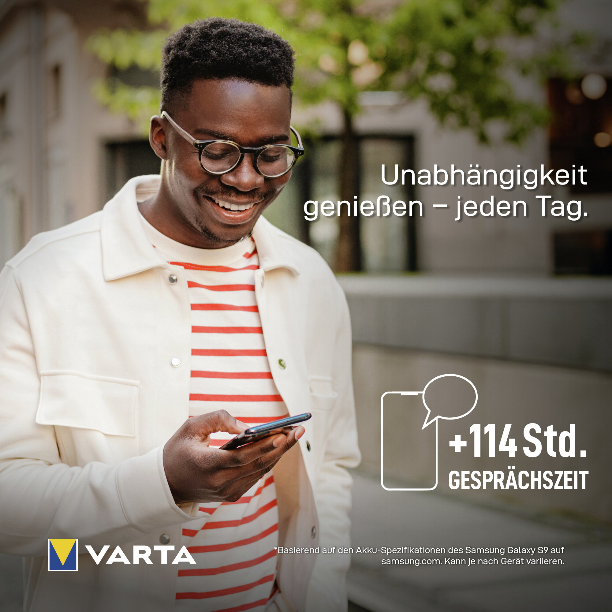 Uomo con occhiali e maglietta a righe tiene smartphone. Logo Varta.
