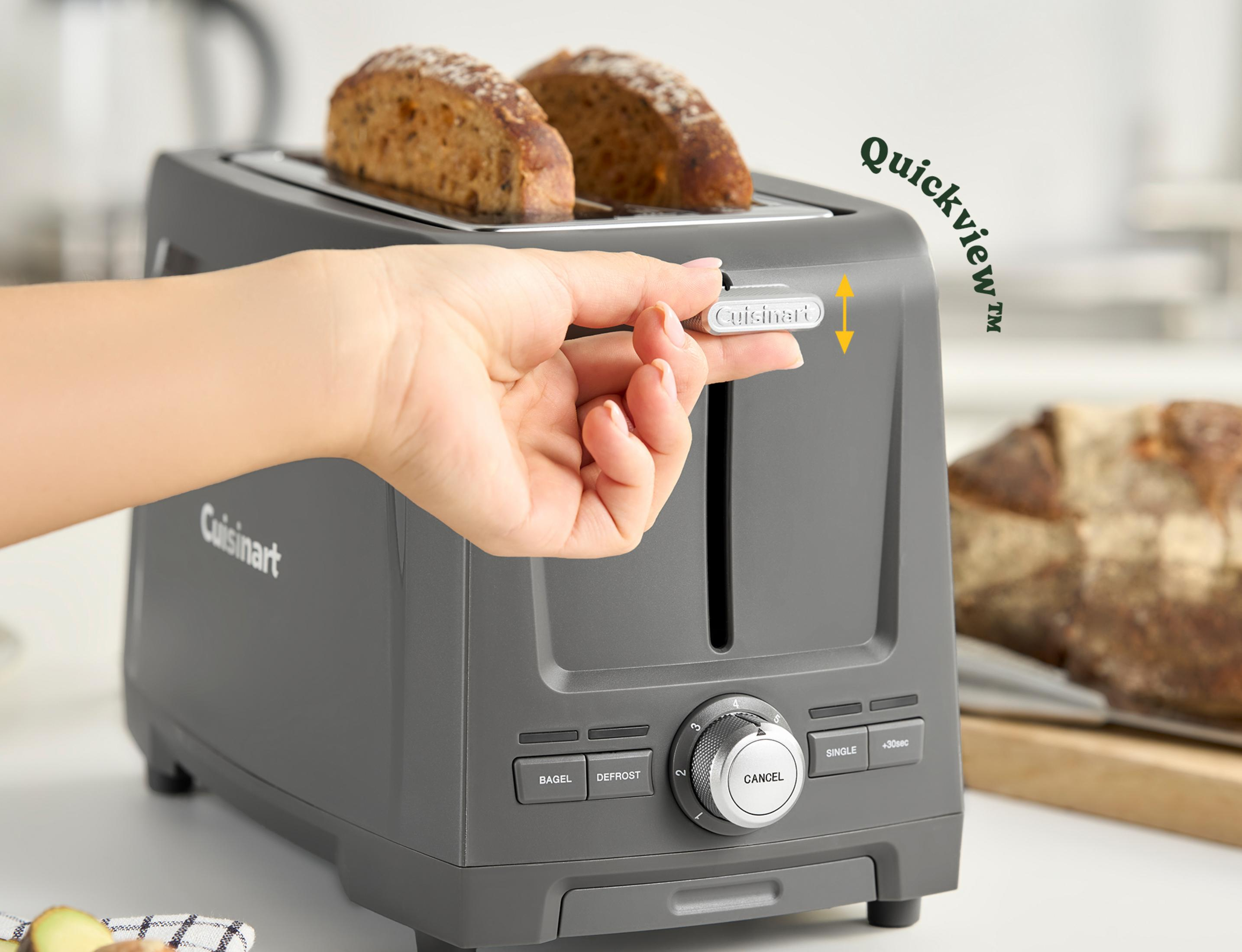 Tostapane grigio con due fette di pane, una mano aziona la leva.