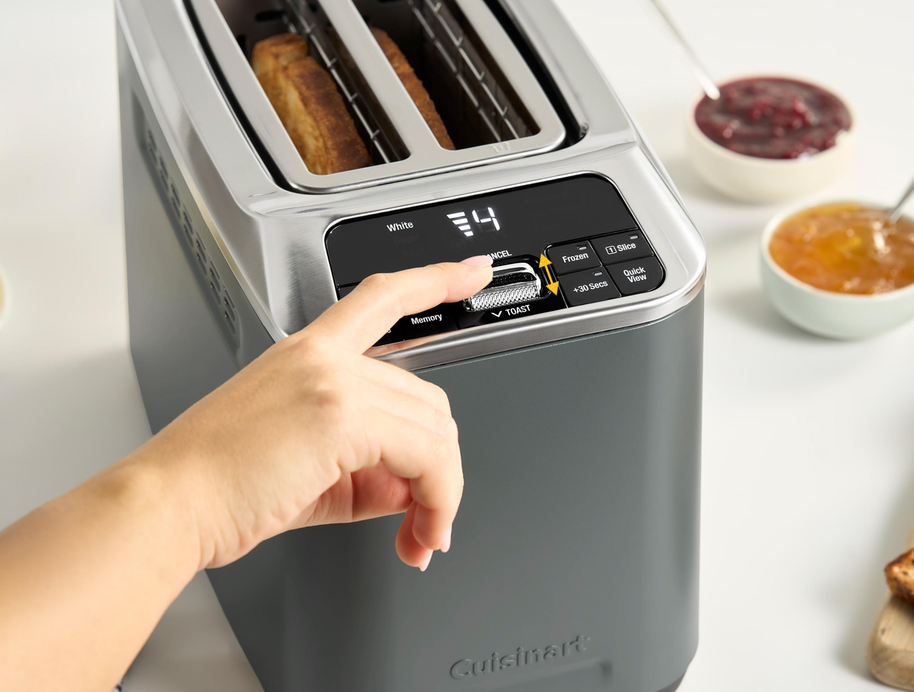 Una mano regola il livello di doratura a 4 su un tostapane. Si vedono toast.