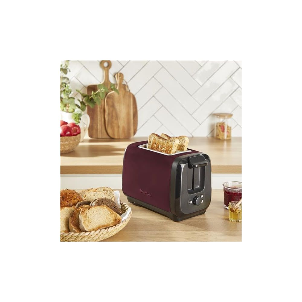Un tostapane bordeaux con toast, pane in un cesto e marmellata.