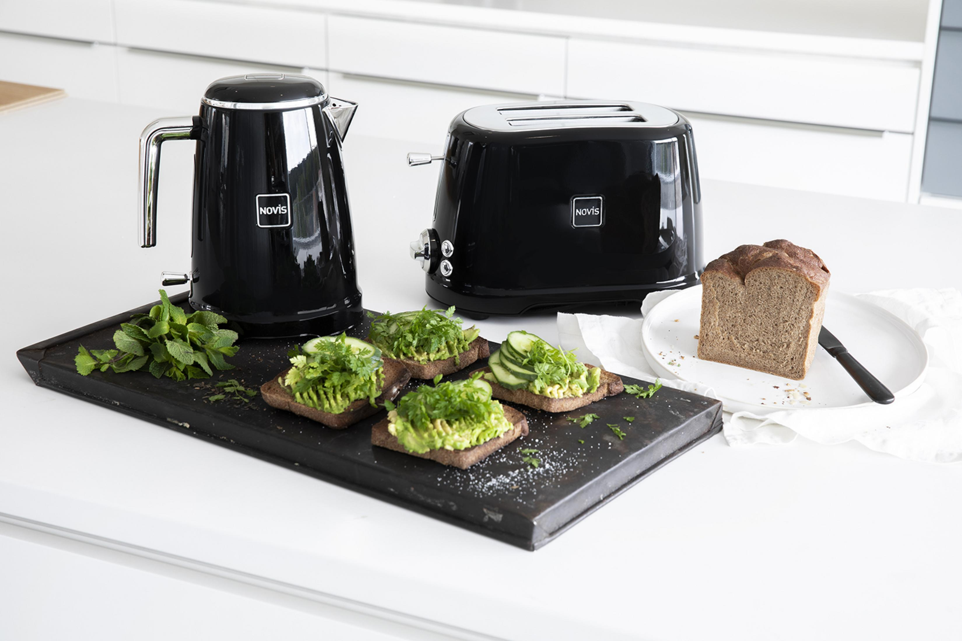 Bollitore e tostapane neri con toast di avocado e pane.