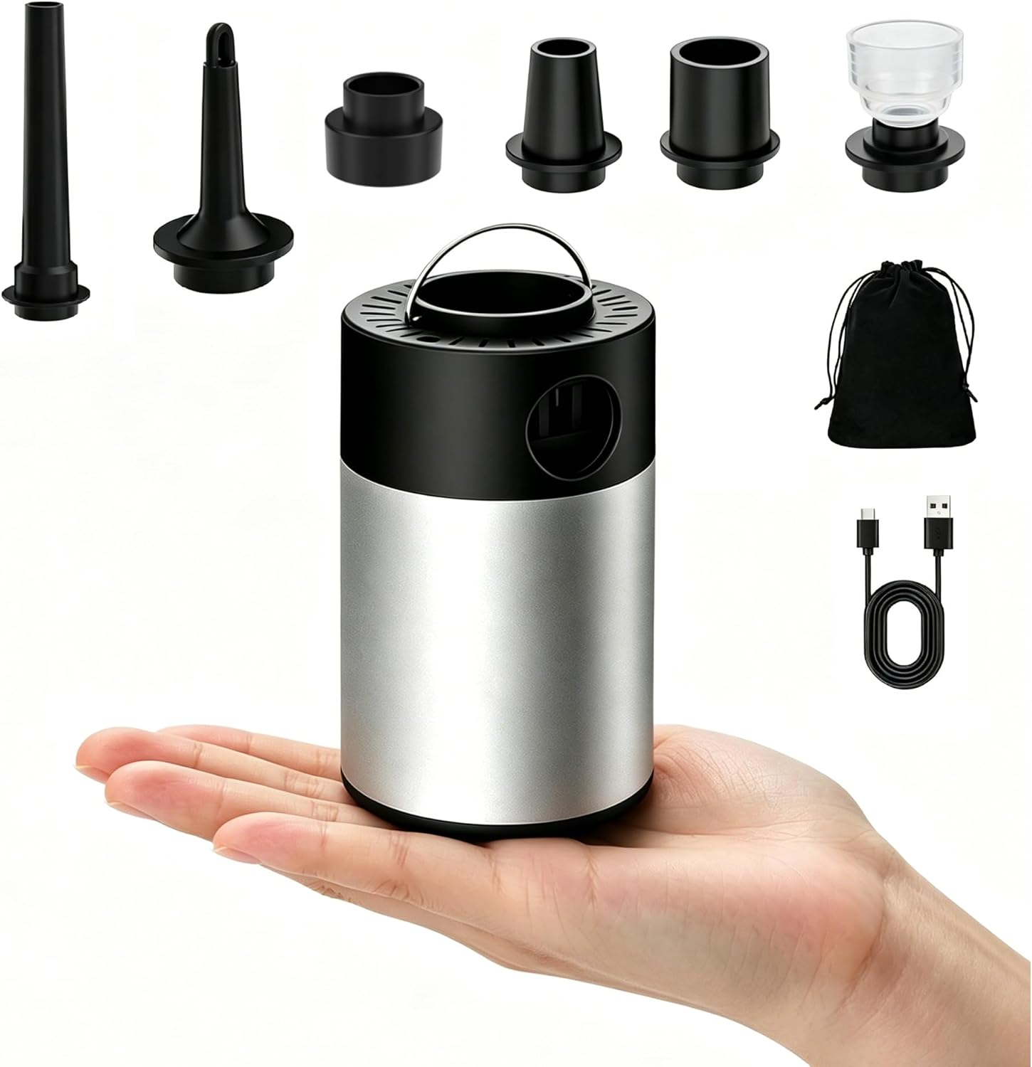 Eine Hand hält eine silberne und schwarze tragbare Luftpumpe mit verschiedenen Düsen, einem schwarzen Beutel und einem USB-Kabel.